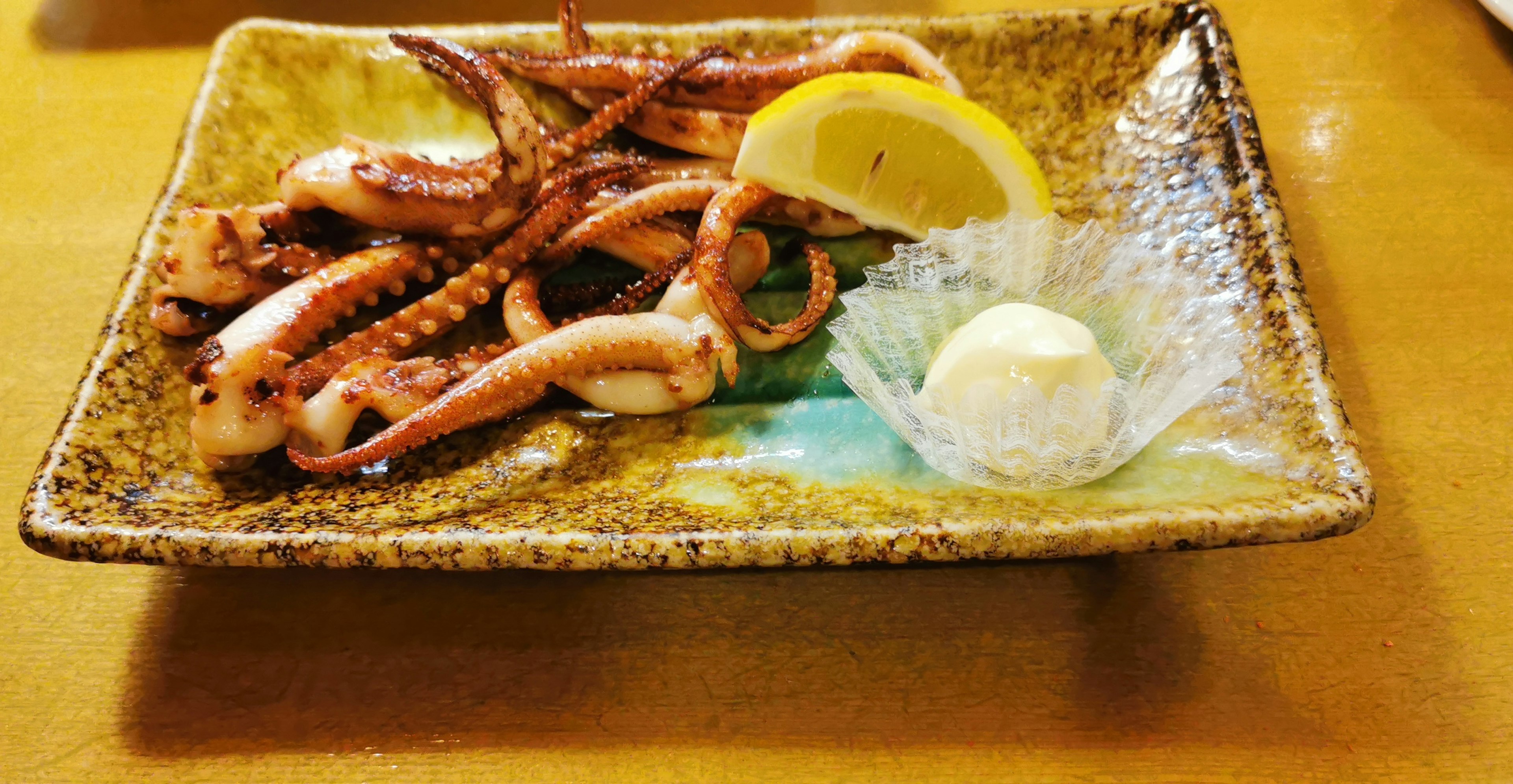 皿に盛られた焼きイカとレモンとバター