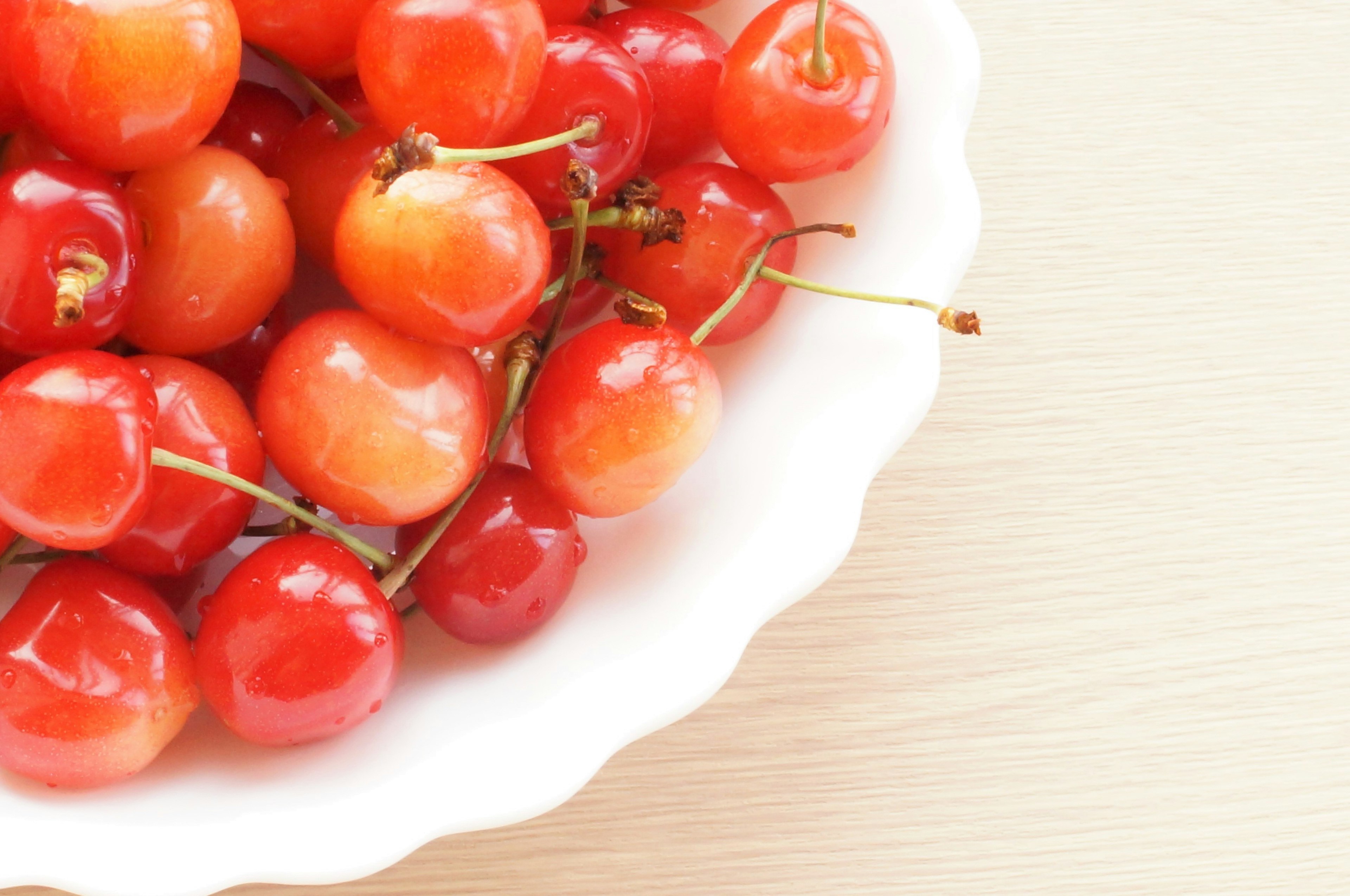 Red cherries arranged in a white bowl