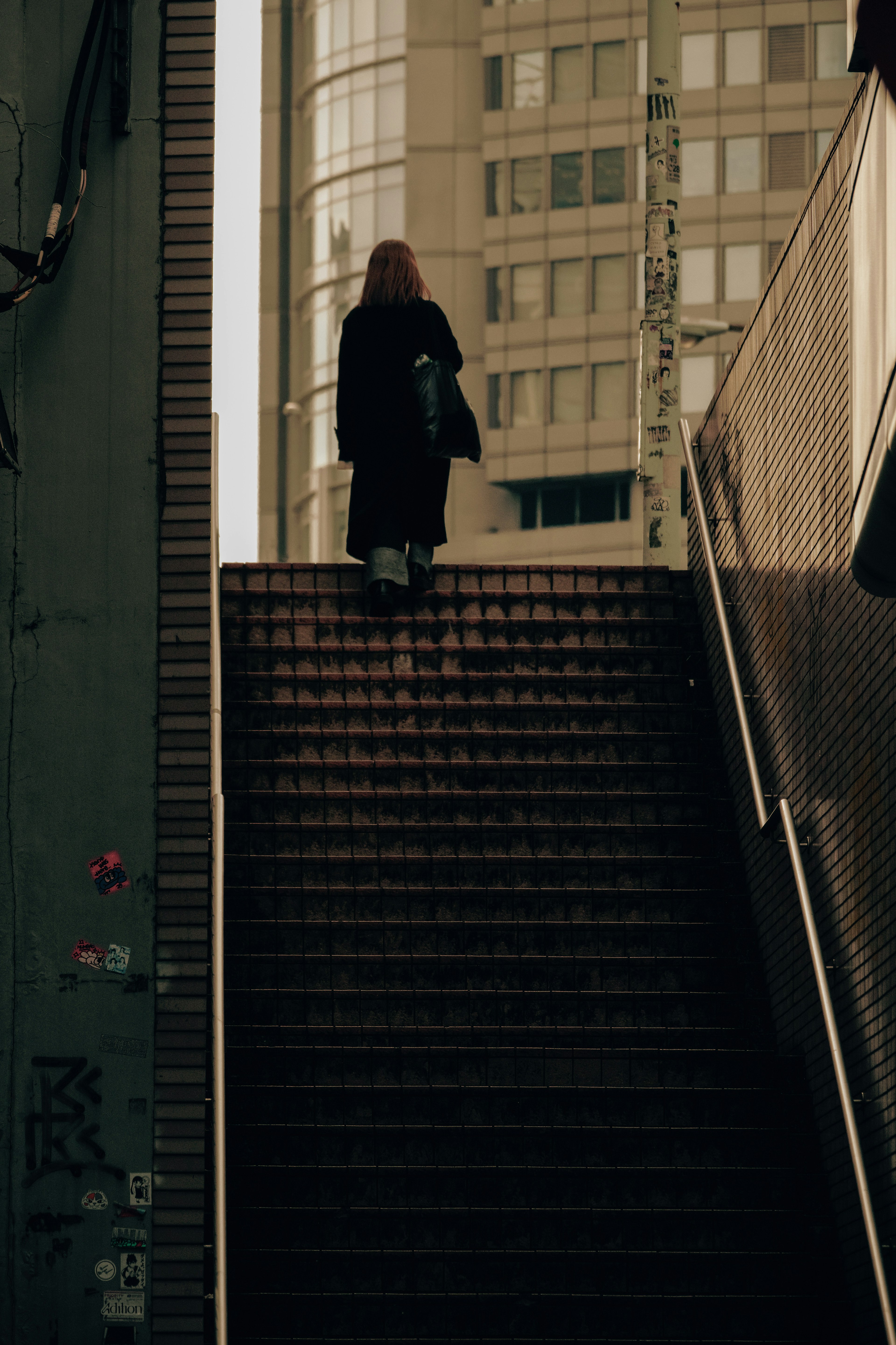 階段を上る女性の後ろ姿と高層ビルの背景