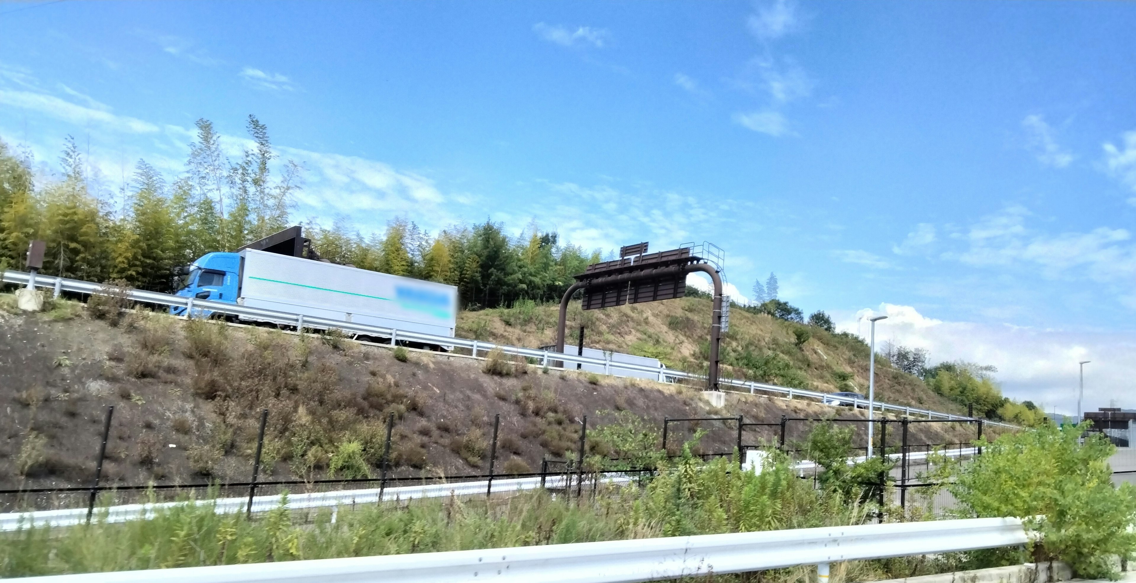 藍色卡車在綠色植物和藍天的道路上行駛