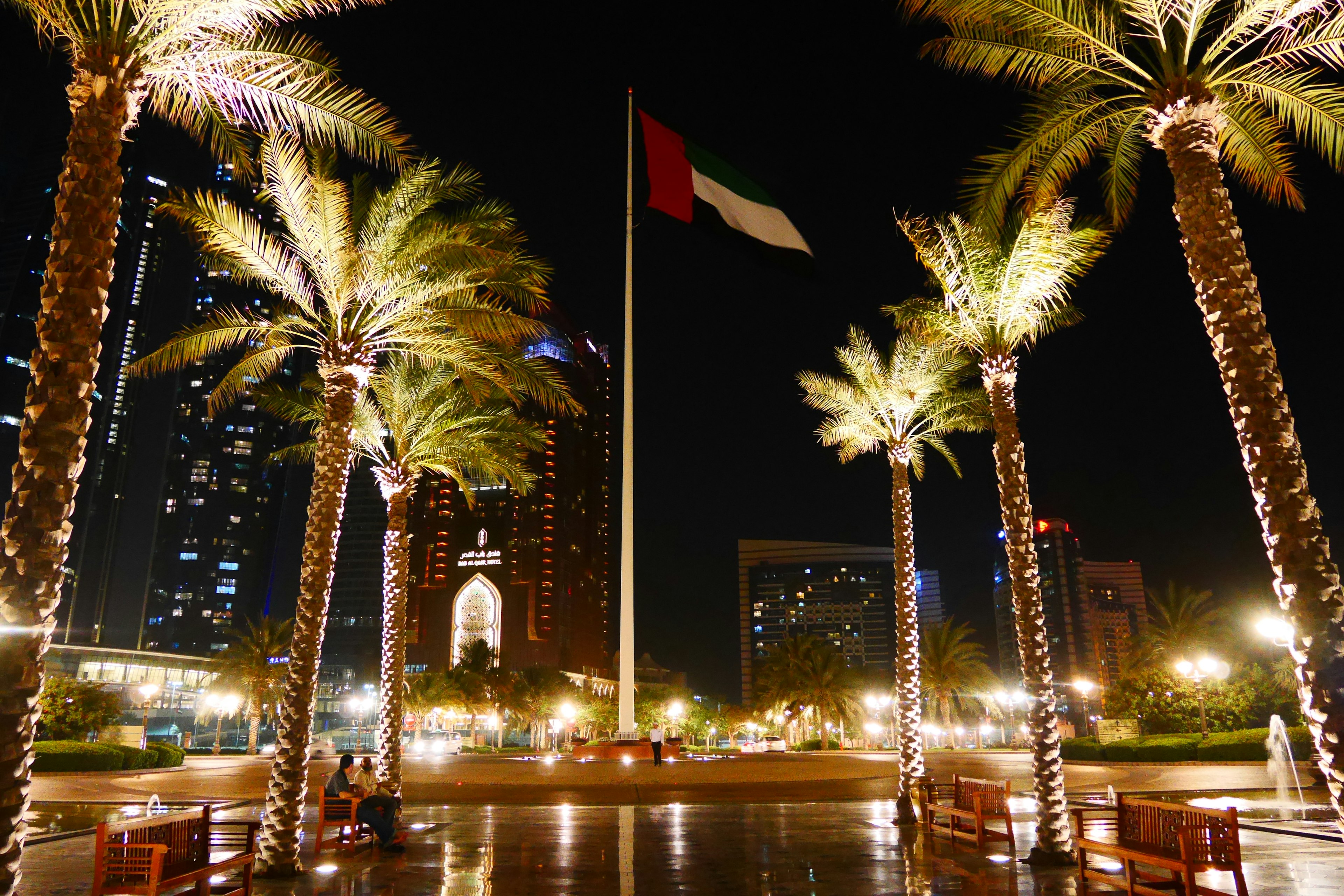 Indonesische Flagge weht nachts umgeben von Palmen und Stadtlichtern