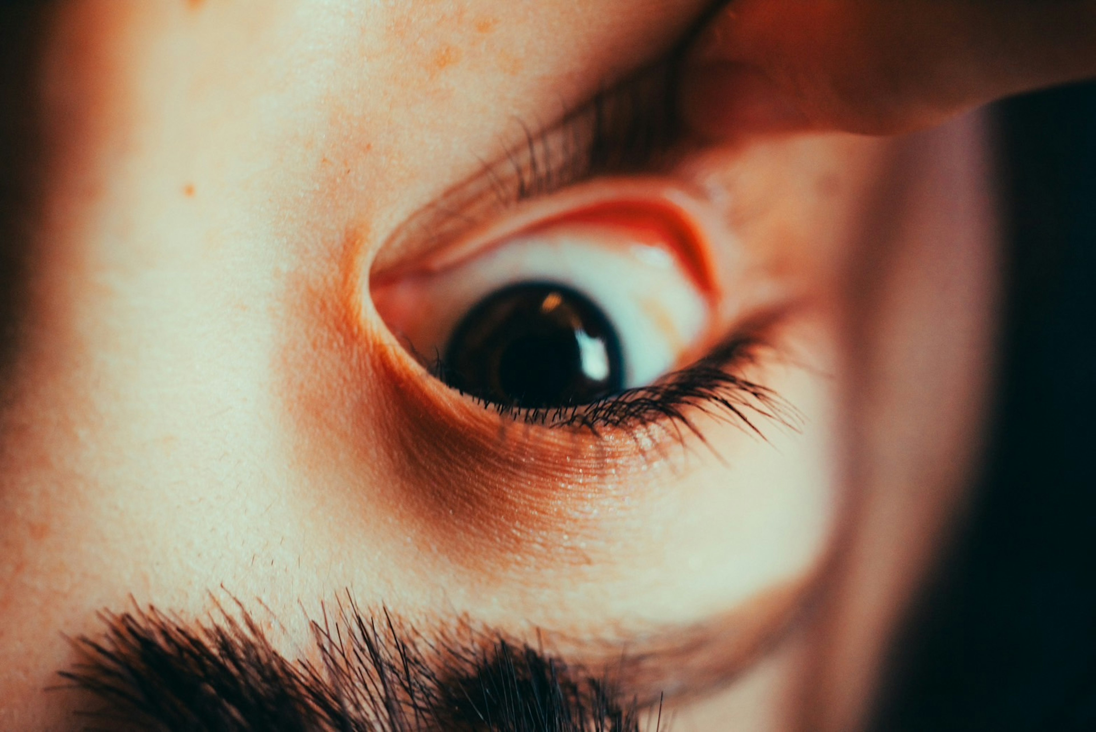 Close-up image of an eye with eyelid being lifted highlighting the dark pupil