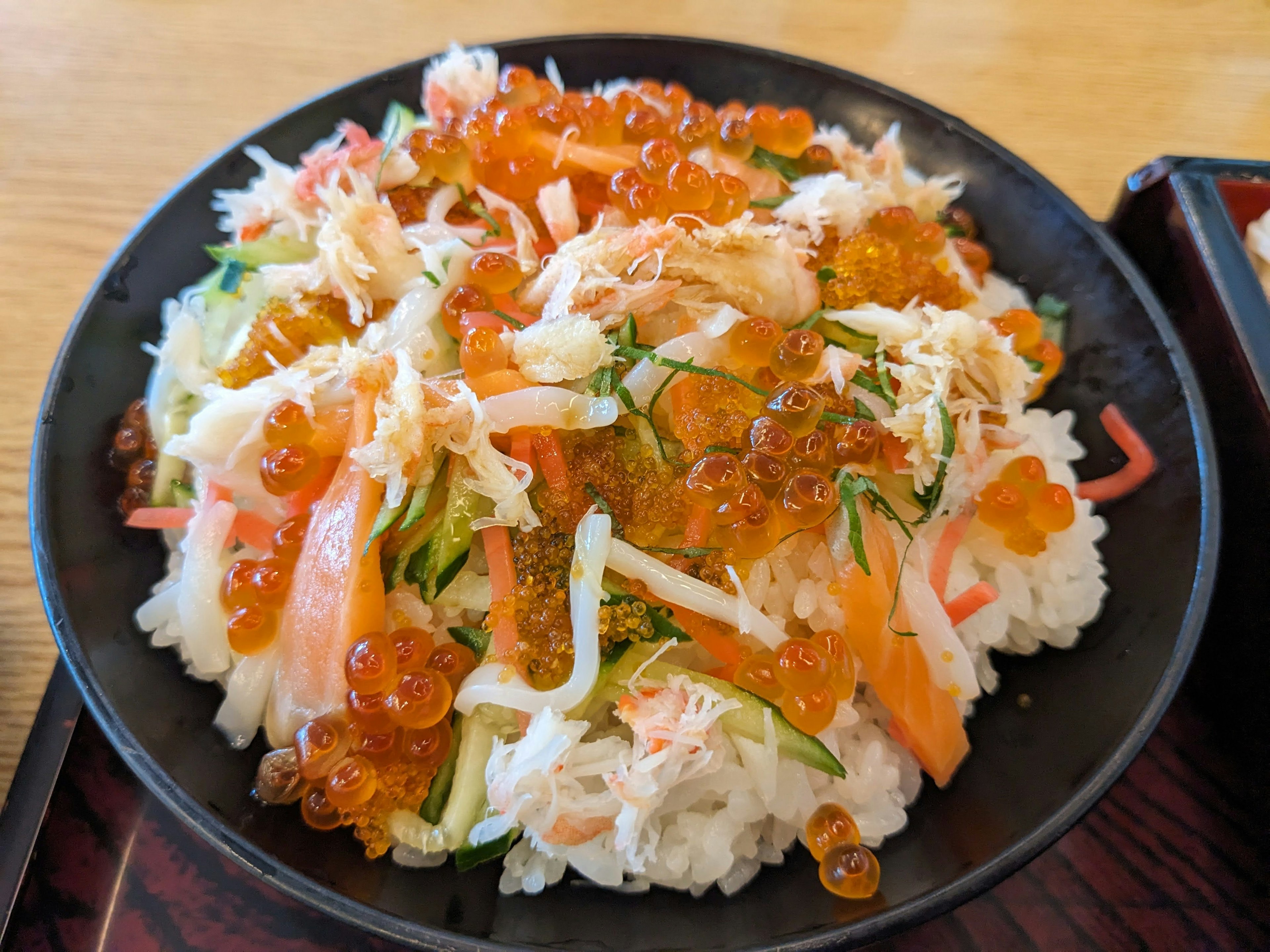 Sushi chirashi cubierto con verduras coloridas y huevas de salmón