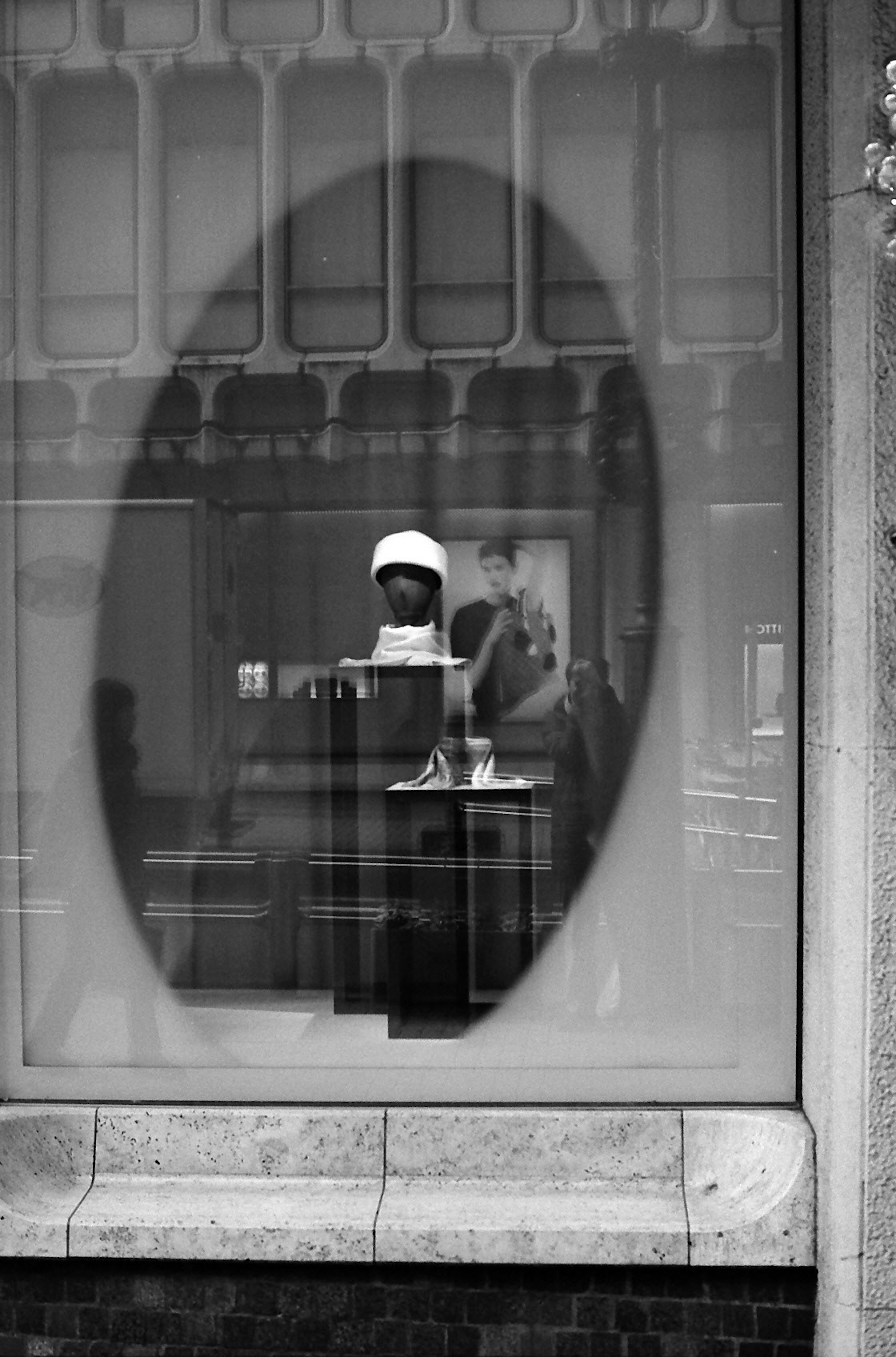 Black and white photo showing a person visible through a window framed in an oval shape