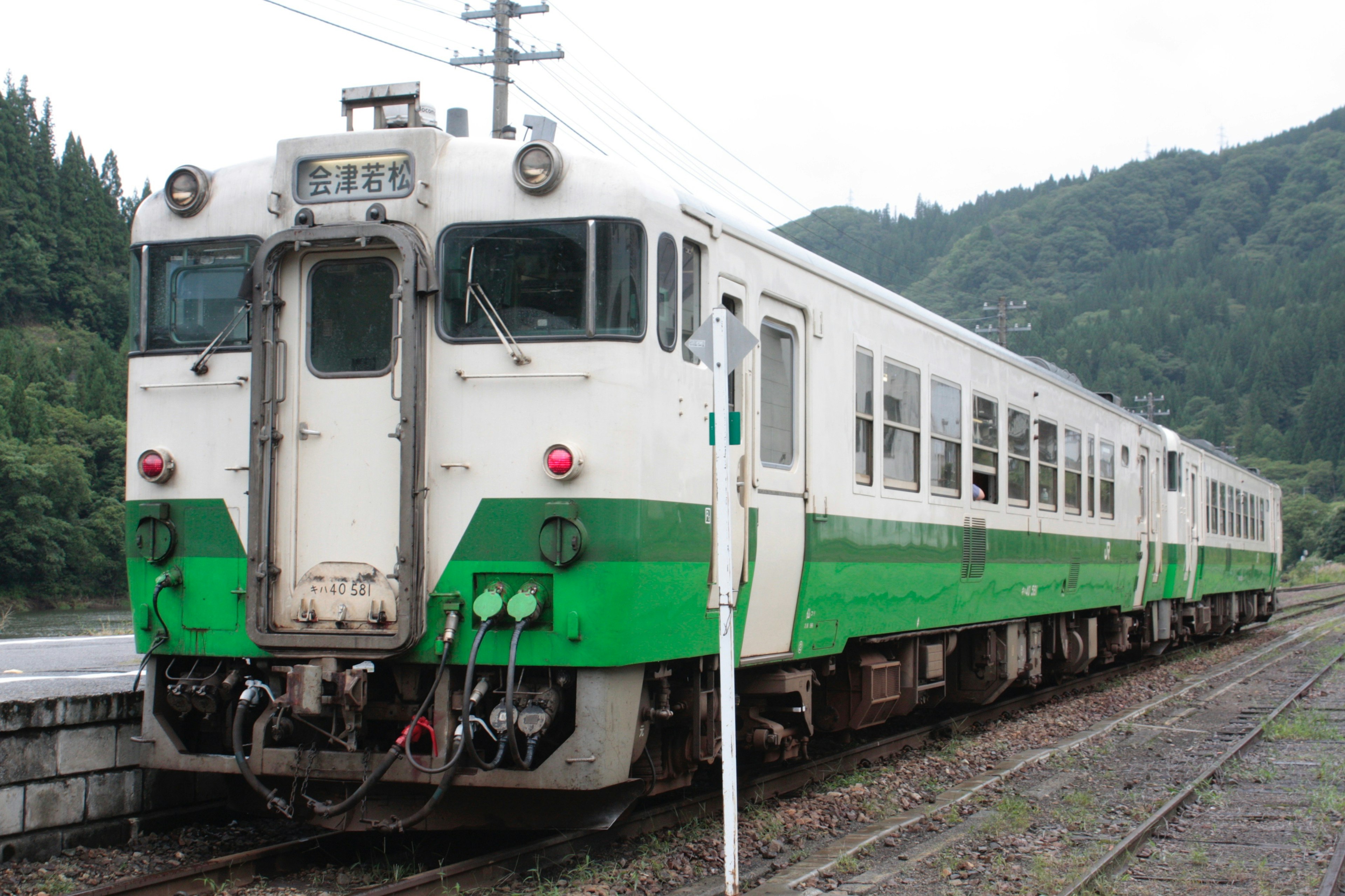 A green and white painted train parked at a station