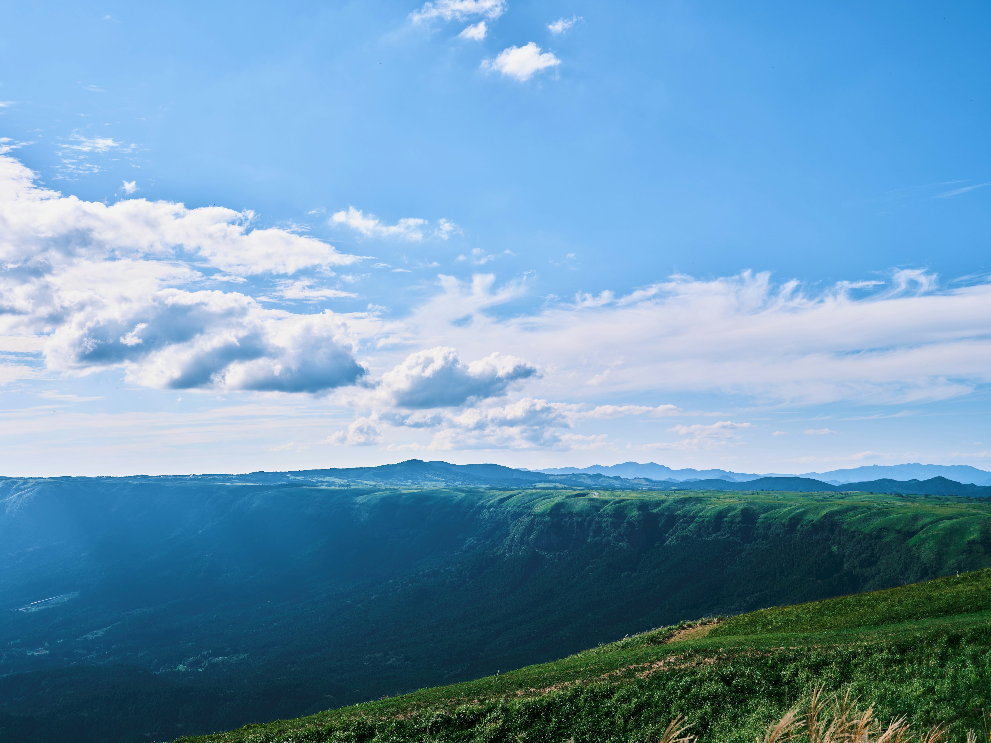 Vista panoramica di montagne verdi sotto un cielo blu con nuvole