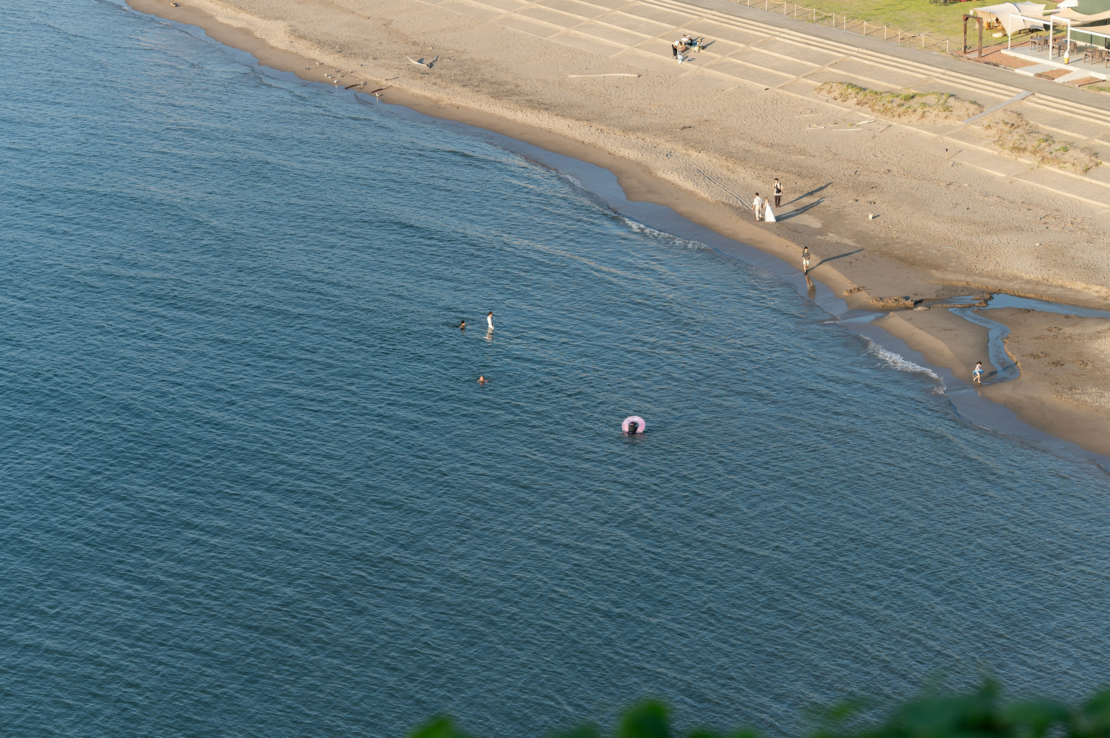 Scena costiera con spiaggia sabbiosa e persone visibili Ombrelloni colorati sulla superficie dell'acqua