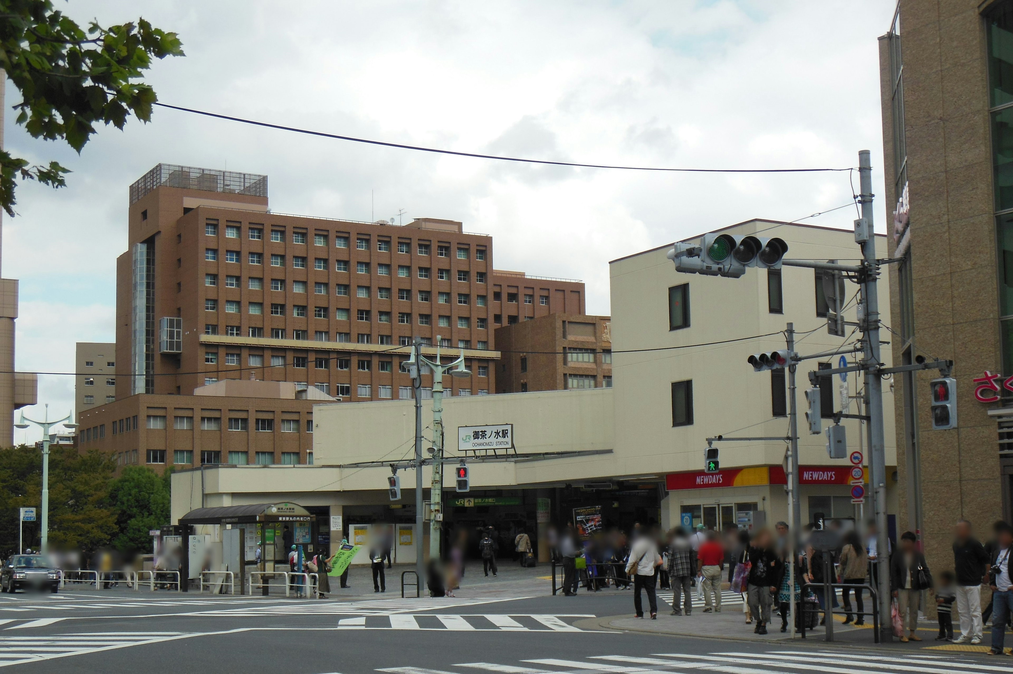 Vista de una intersección concurrida con edificios y una estación de tren