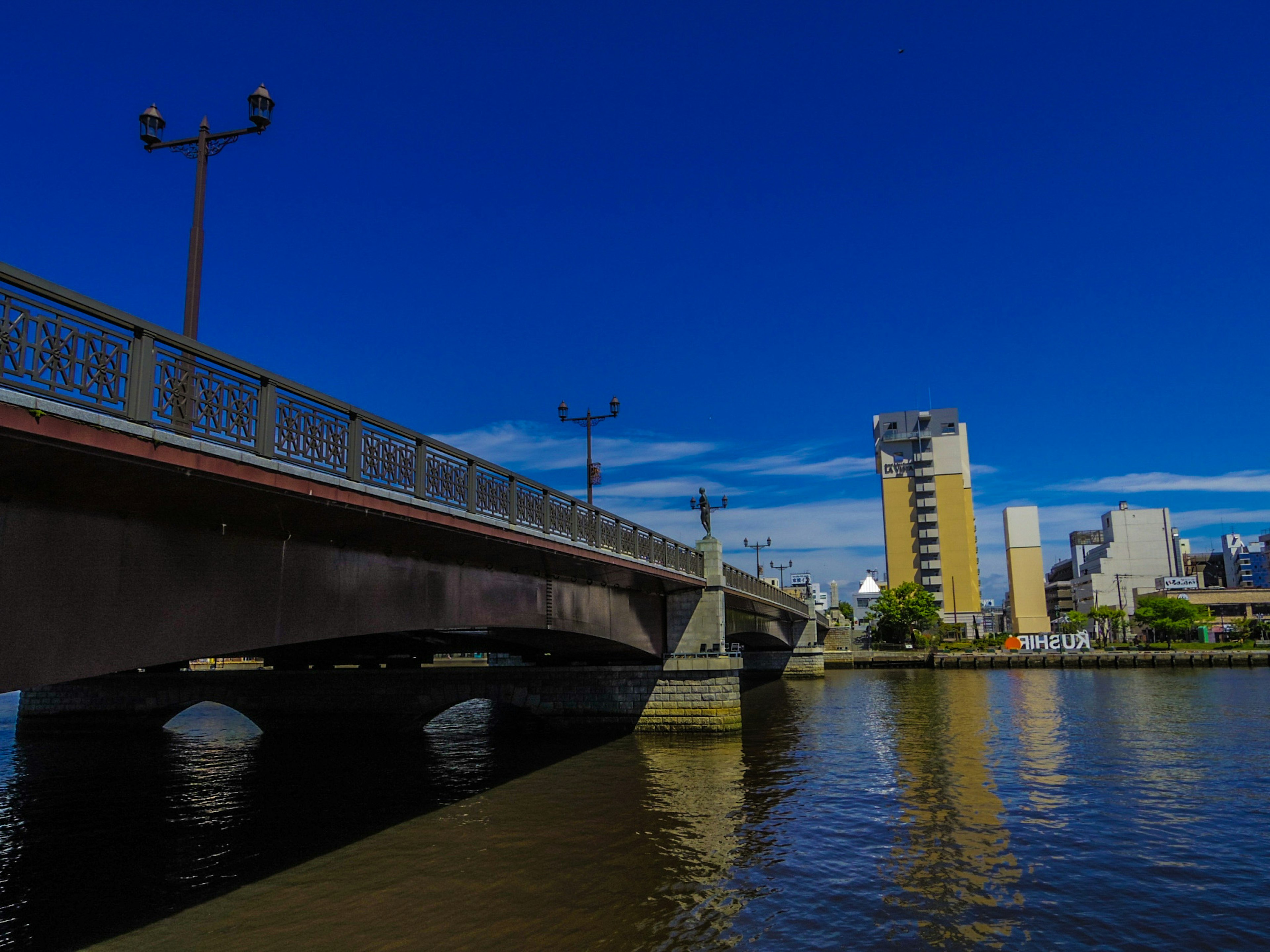 Pemandangan sungai dengan jembatan di bawah langit biru