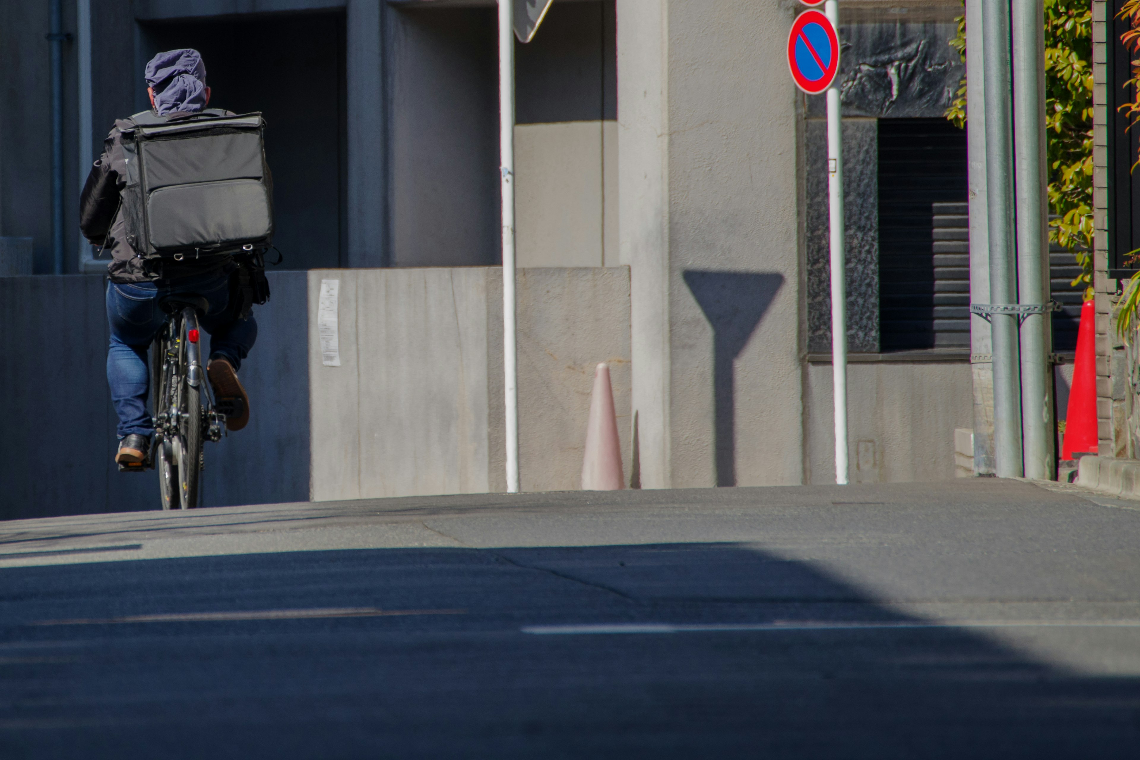 A delivery person riding a bicycle turns at a street corner