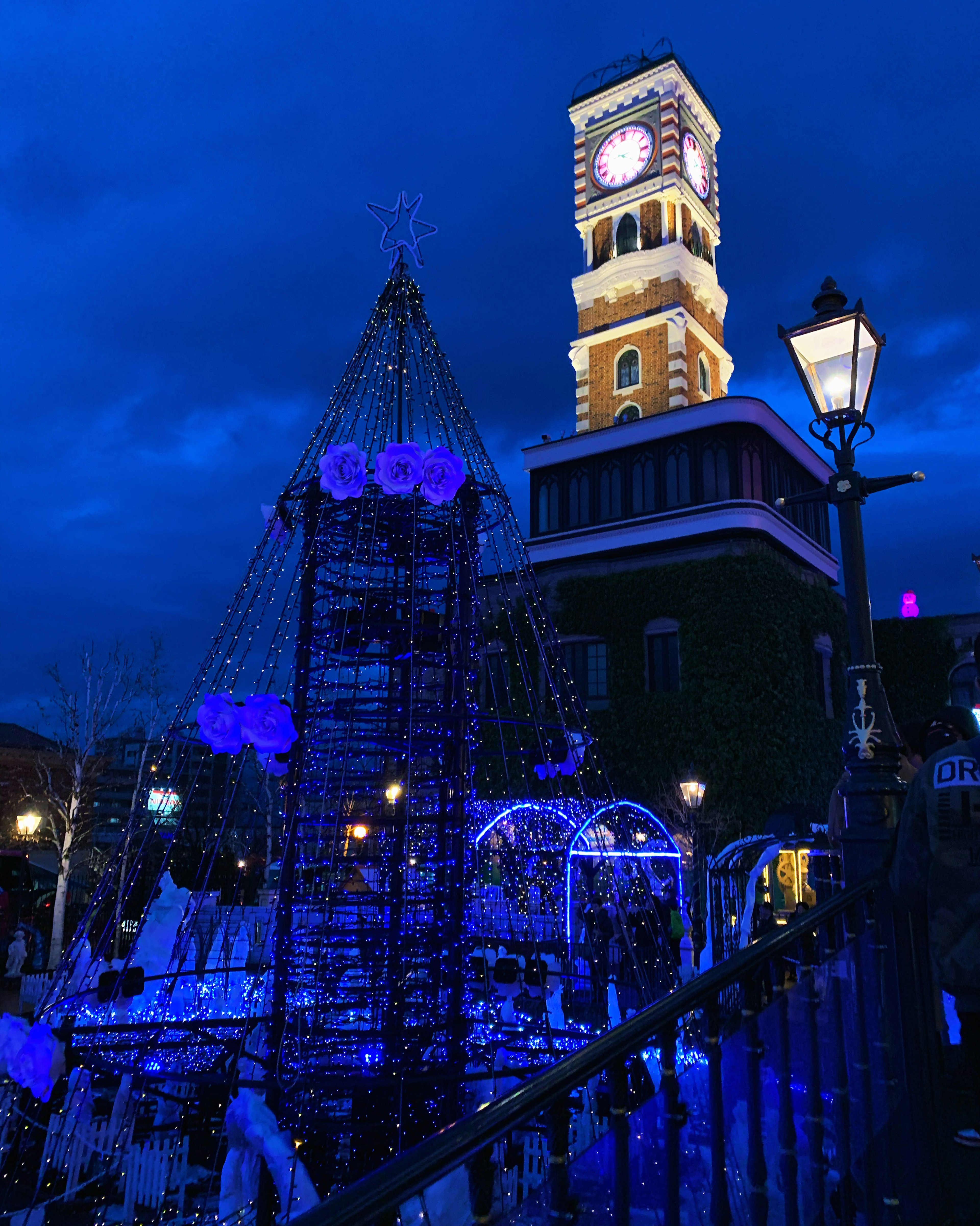 Escena nocturna con una torre iluminada en azul y una fuente decorativa