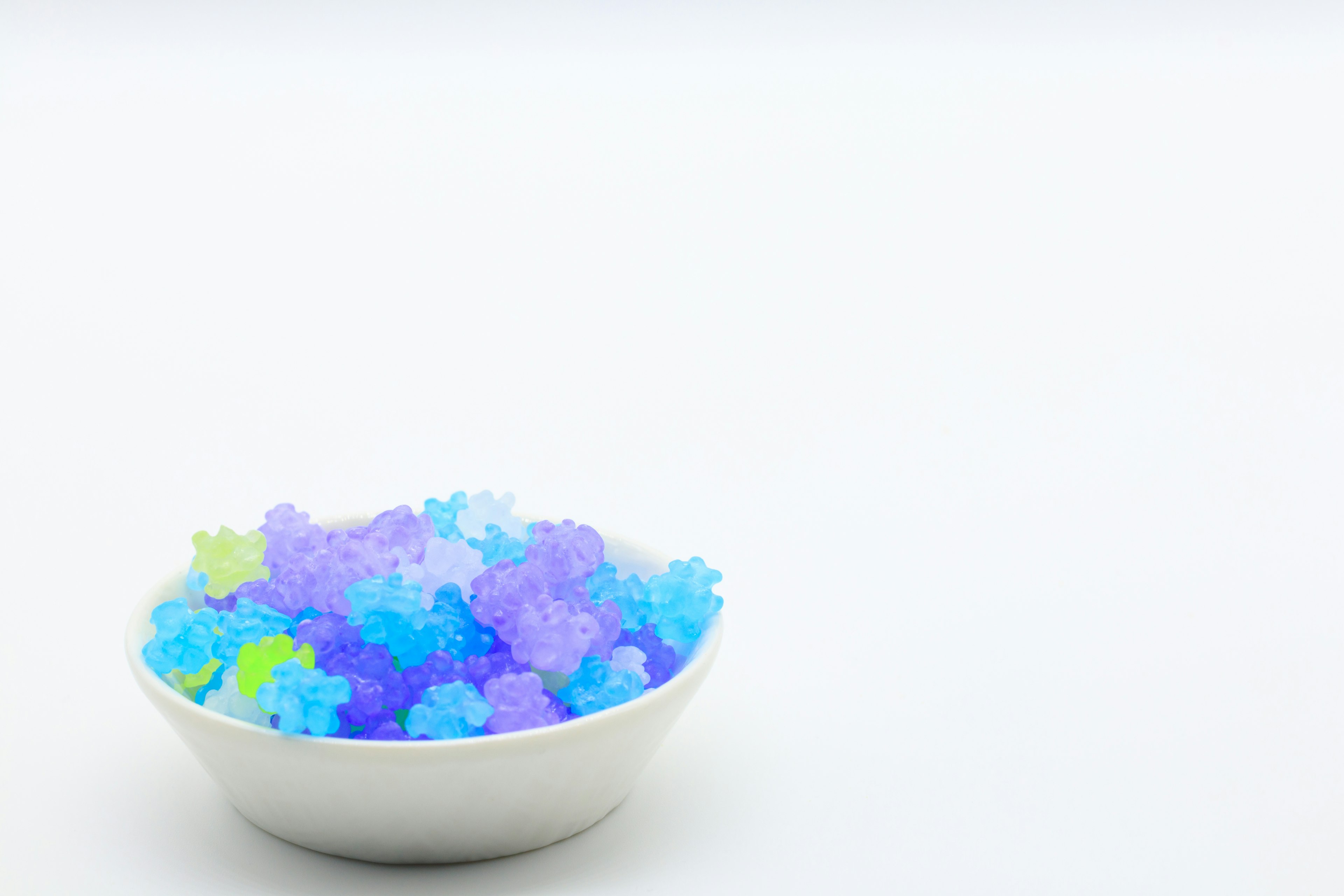 A white bowl filled with colorful star-shaped jelly beans against a white background