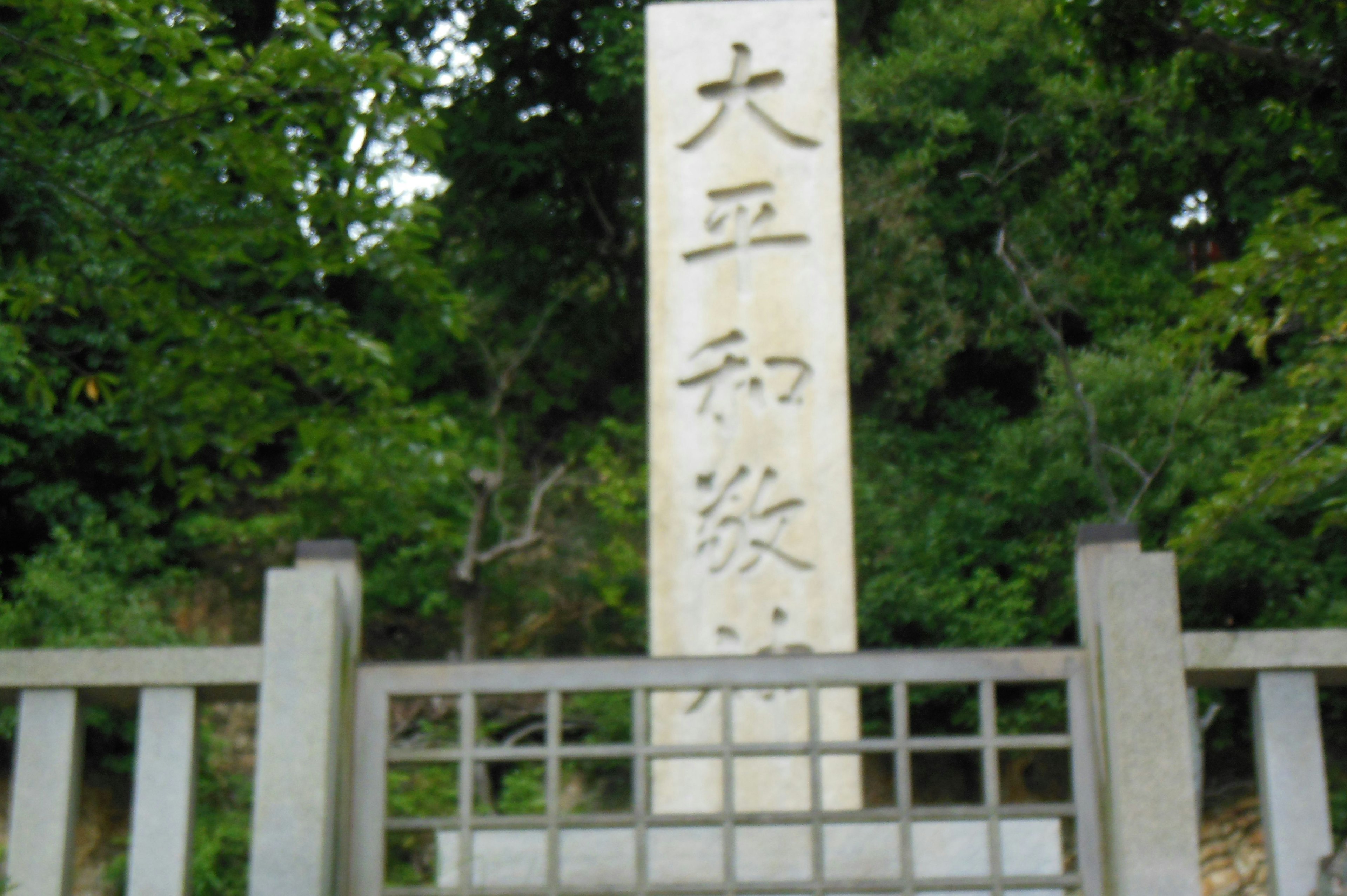 Un monument en pierre avec des inscriptions entouré de verdure