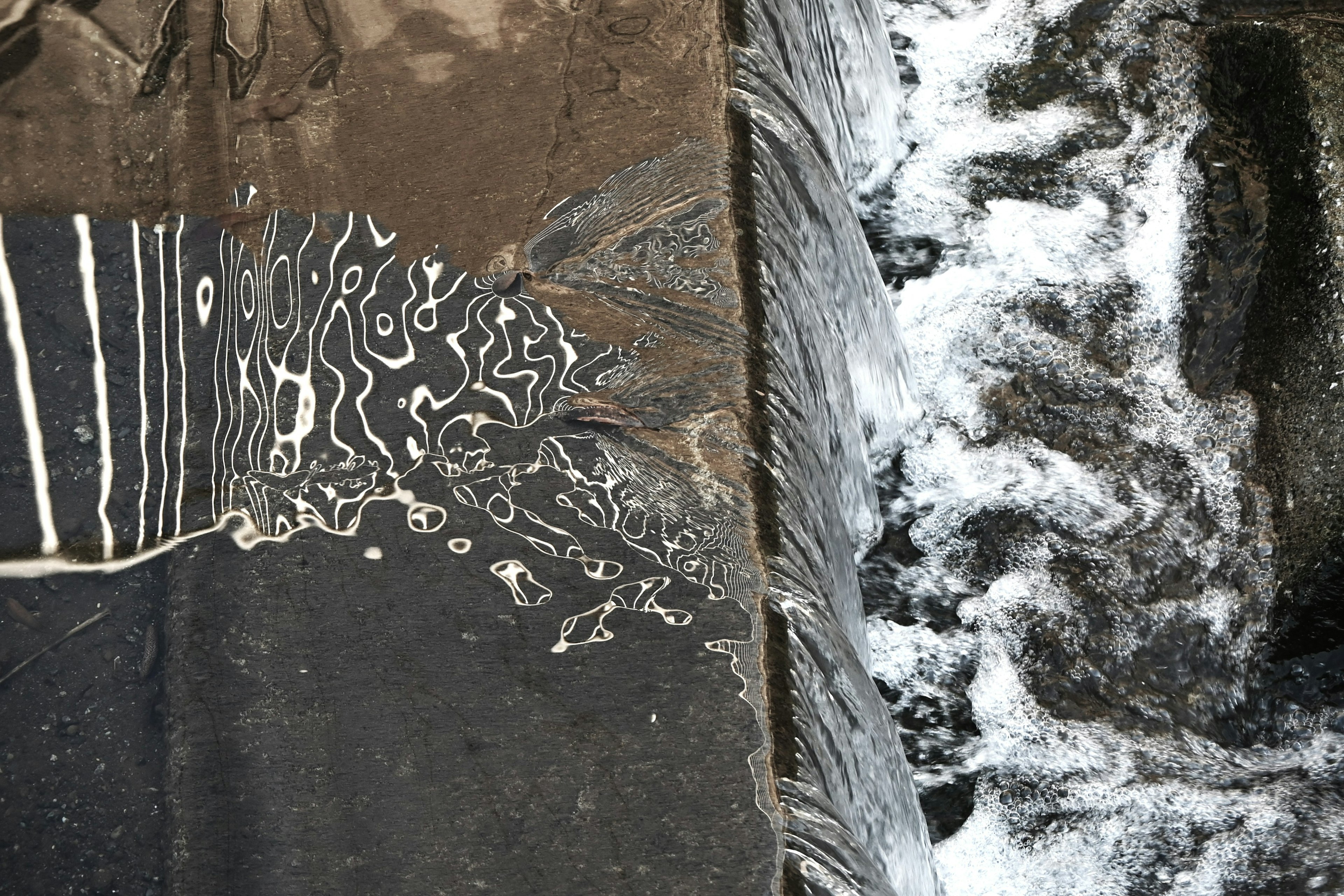 Motifs de vagues réfléchissant sur une surface sombre avec de l'eau courante