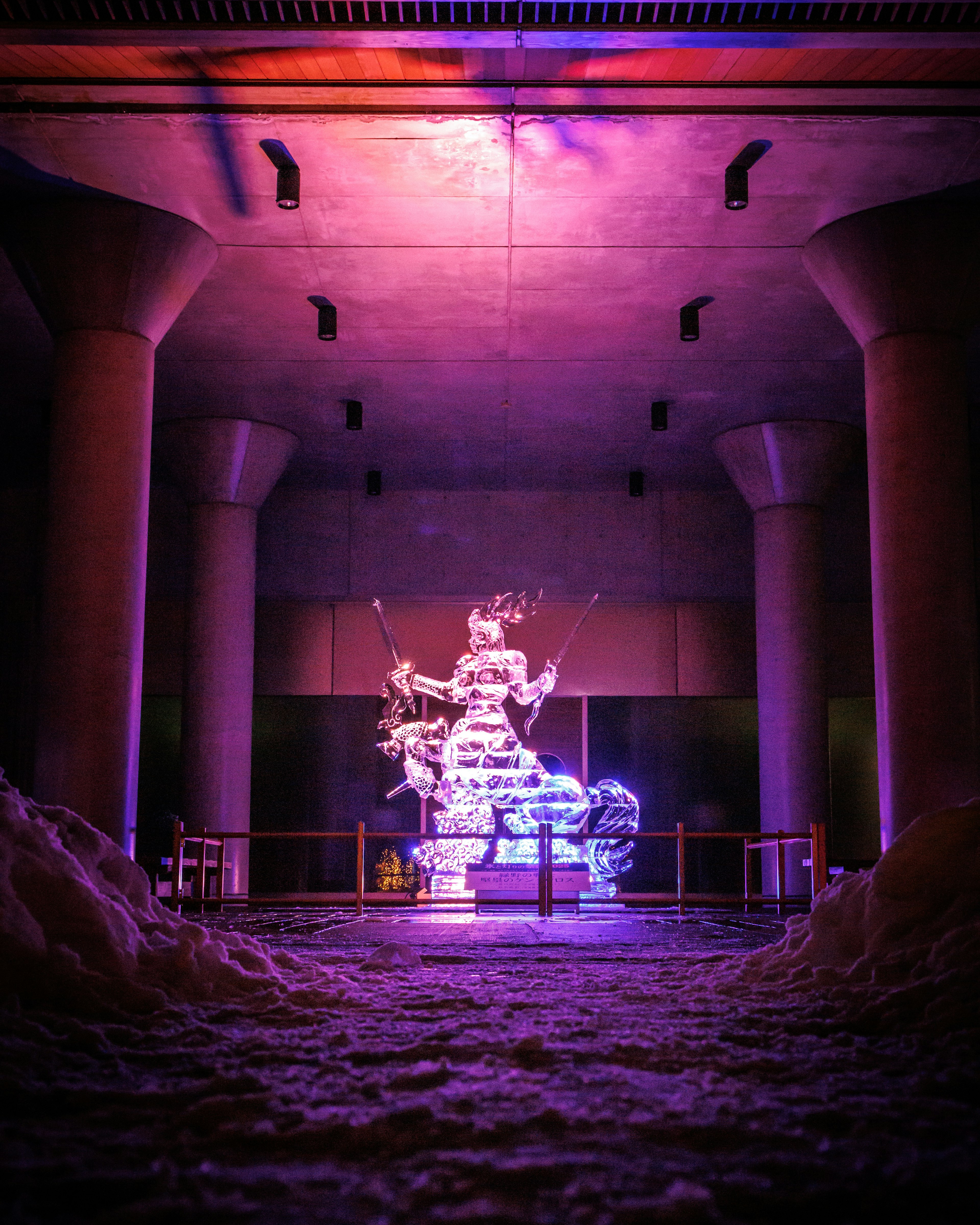 Une sculpture mystique éclairée par des lumières colorées dans un espace sombre