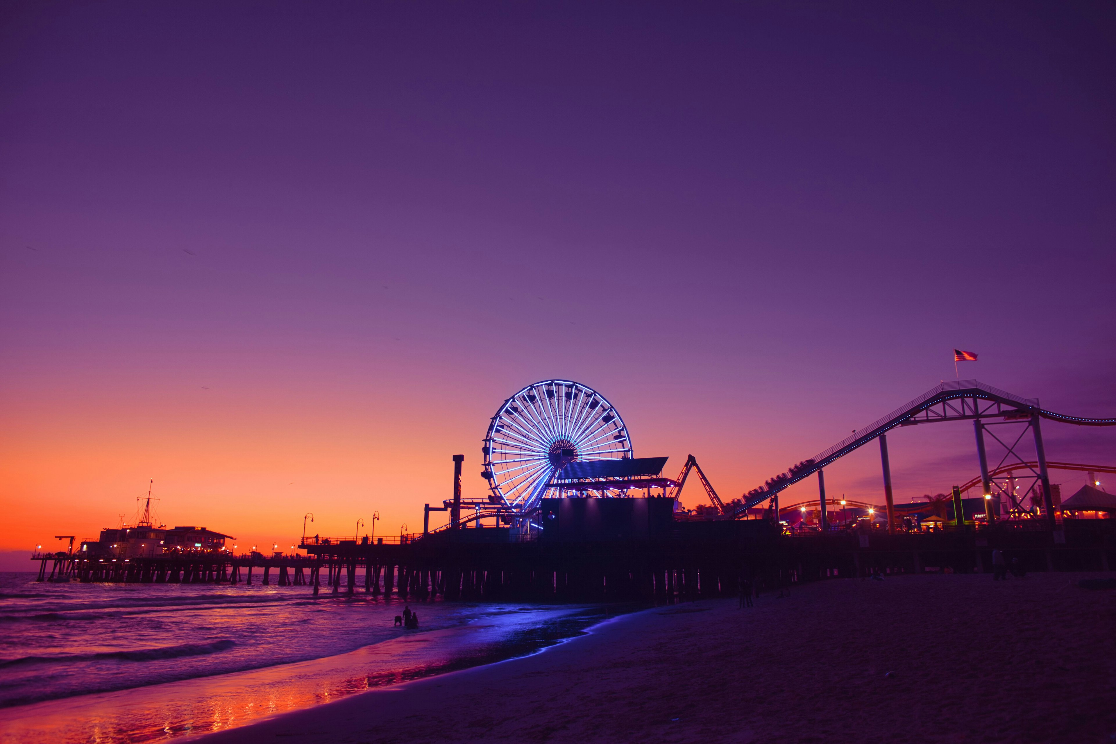 Scène côtière avec une grande roue et un parc d'attractions au coucher du soleil