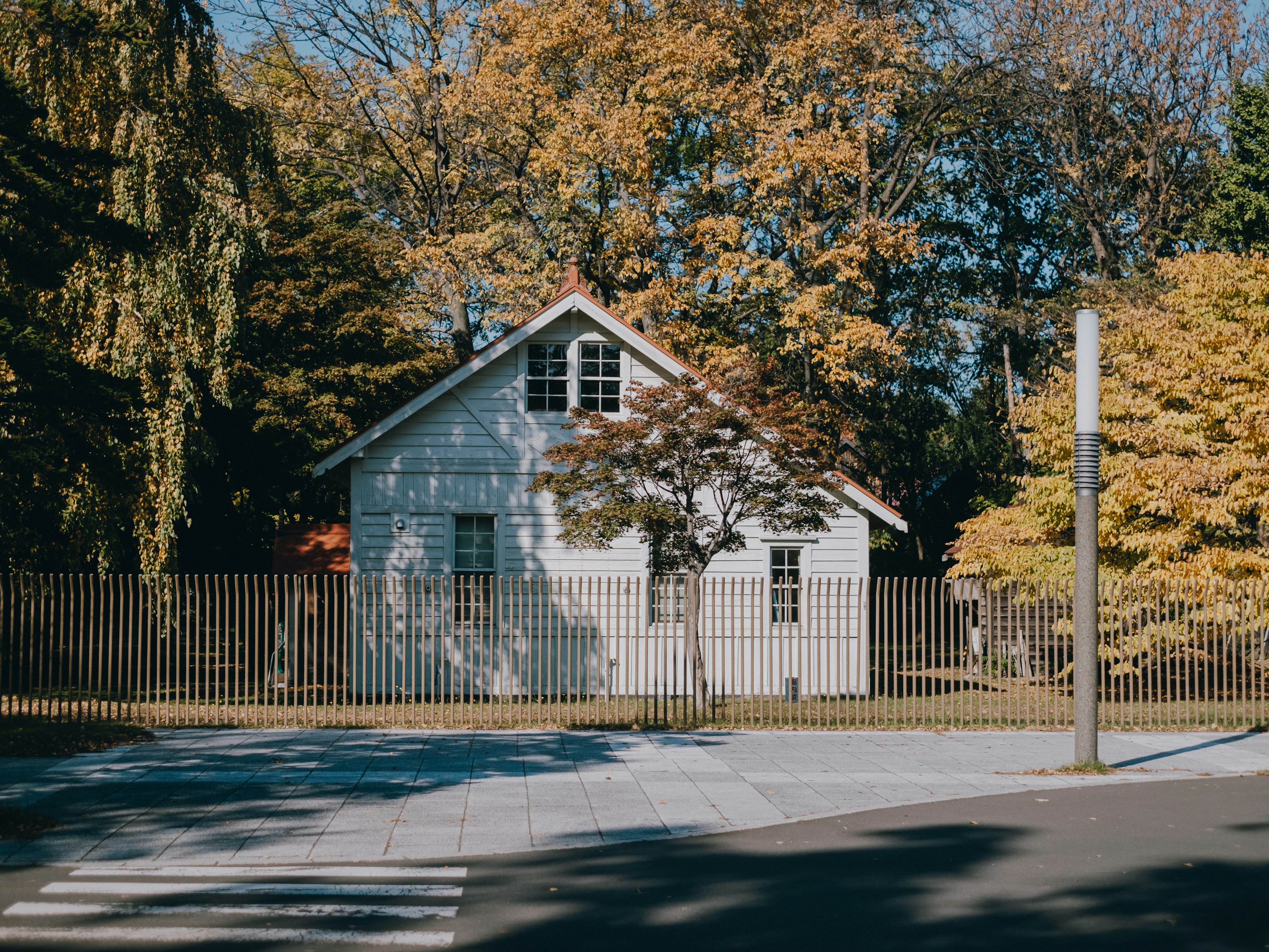 Exterior of a white house surrounded by autumn-colored trees