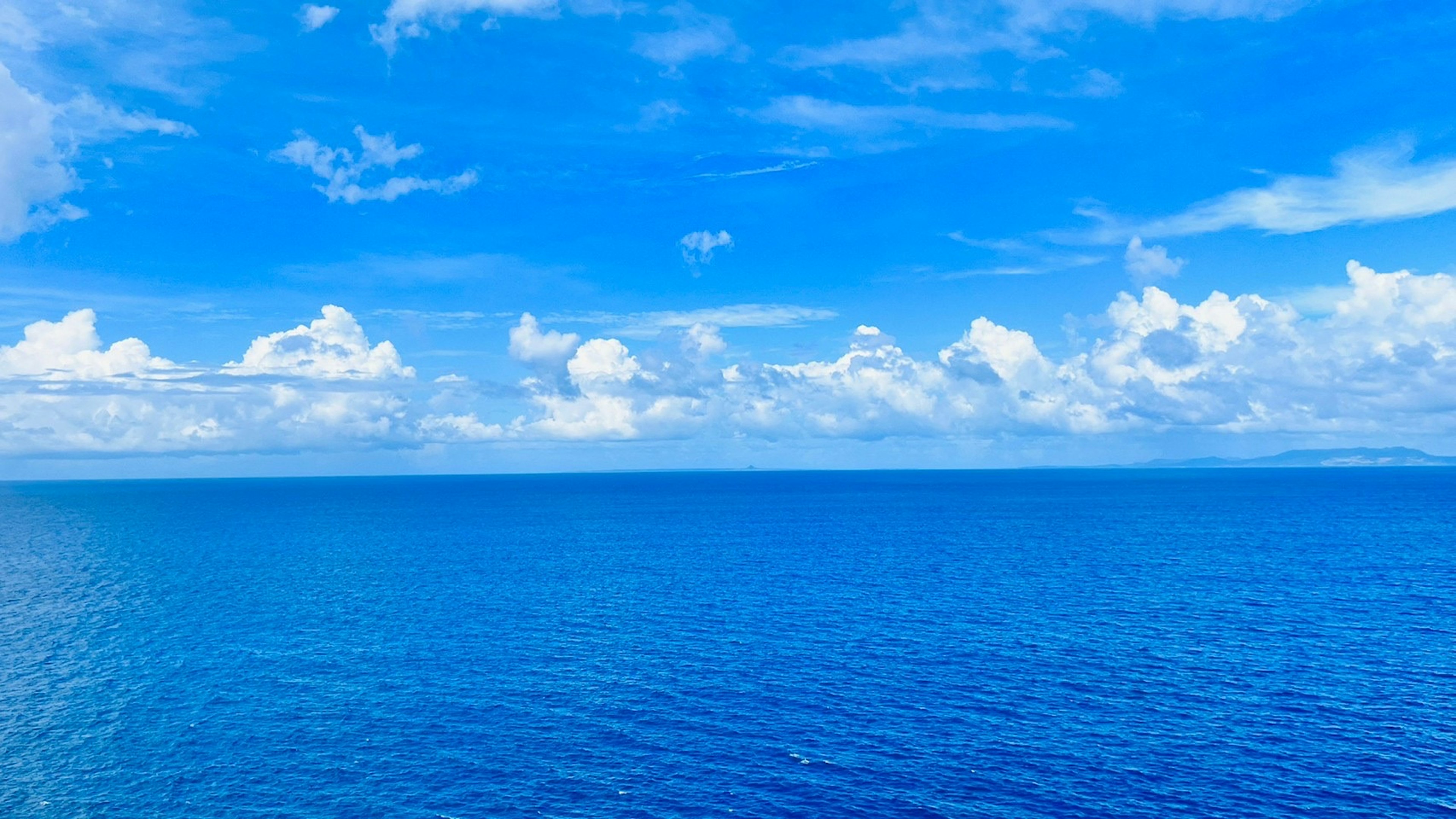 Vaste océan bleu sous un ciel clair avec des nuages blancs