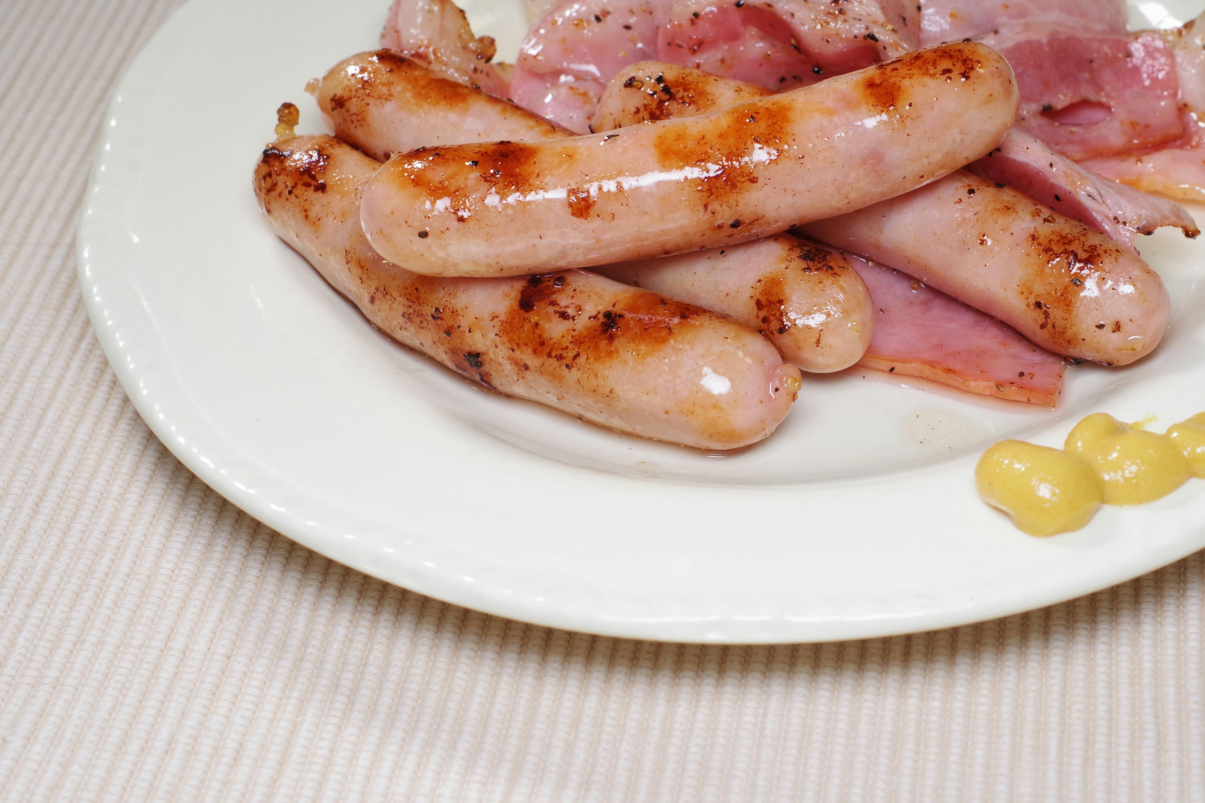 A plate of grilled sausages and ham slices