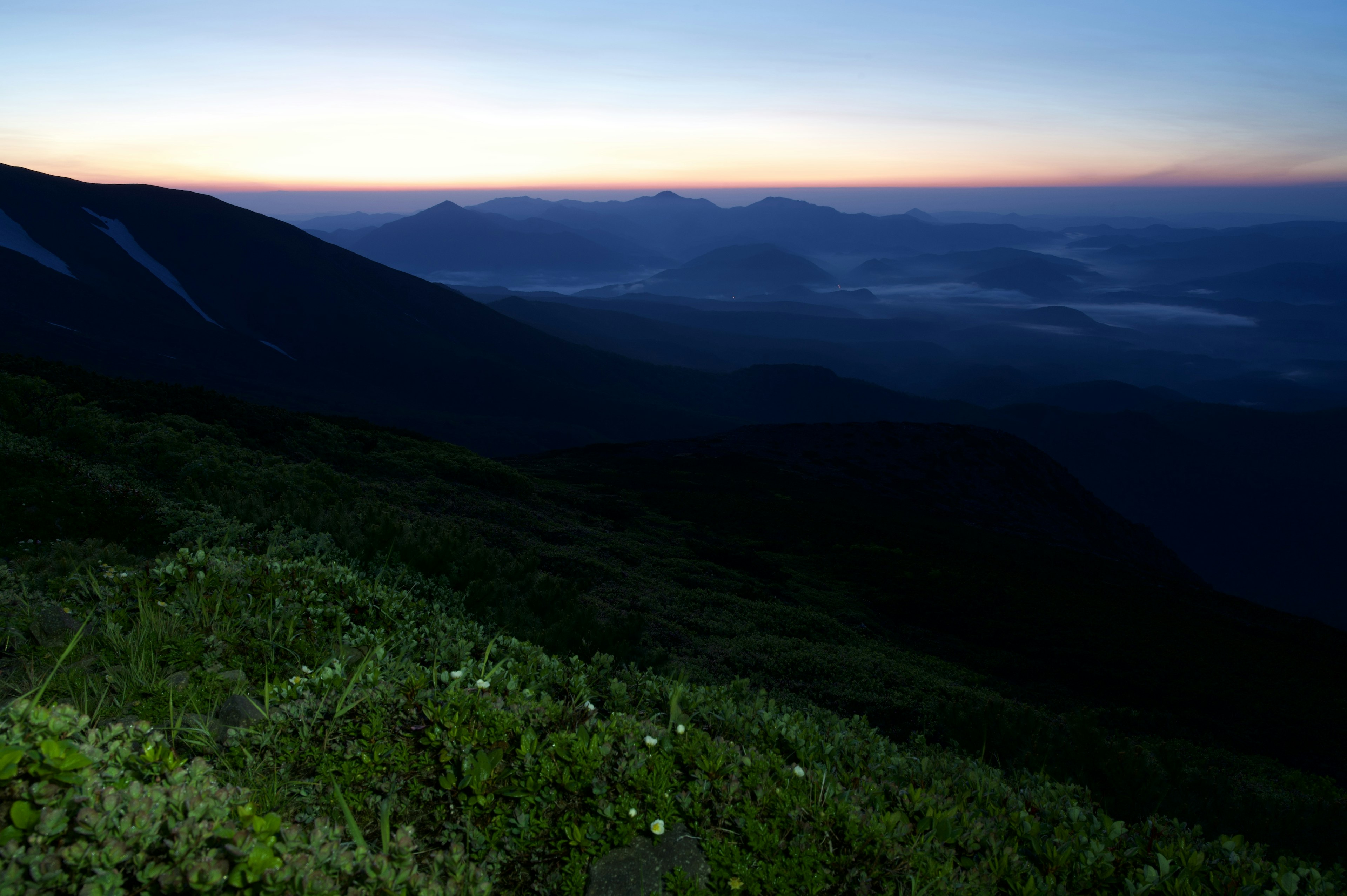 美しい日の出の瞬間を捉えた山の景色 濃い緑の草原と遠くの山々が見える