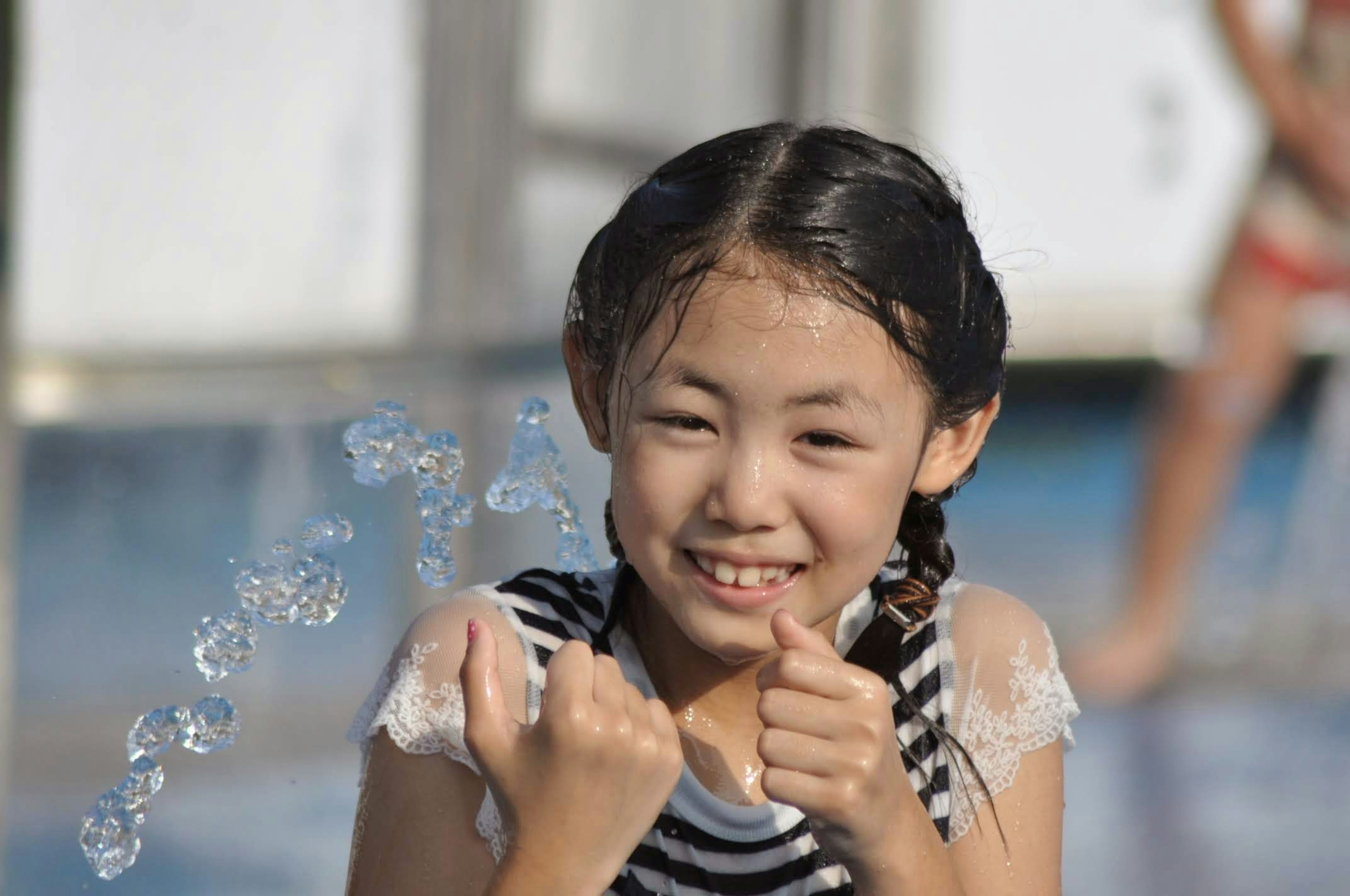 Una ragazza sorridente che gioca nell'acqua cercando di afferrare delle bolle