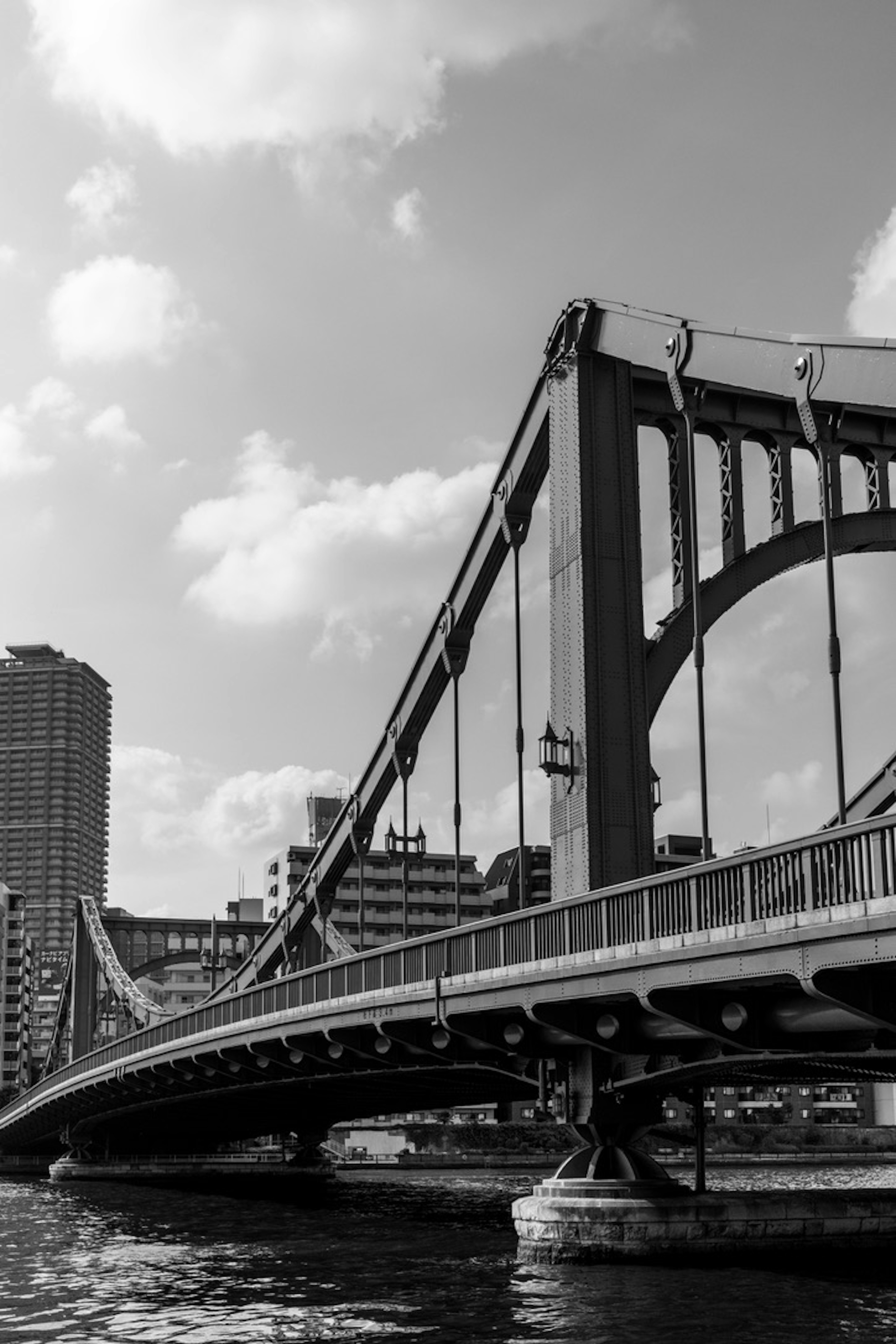 Black and white image of a bridge structure with urban scenery