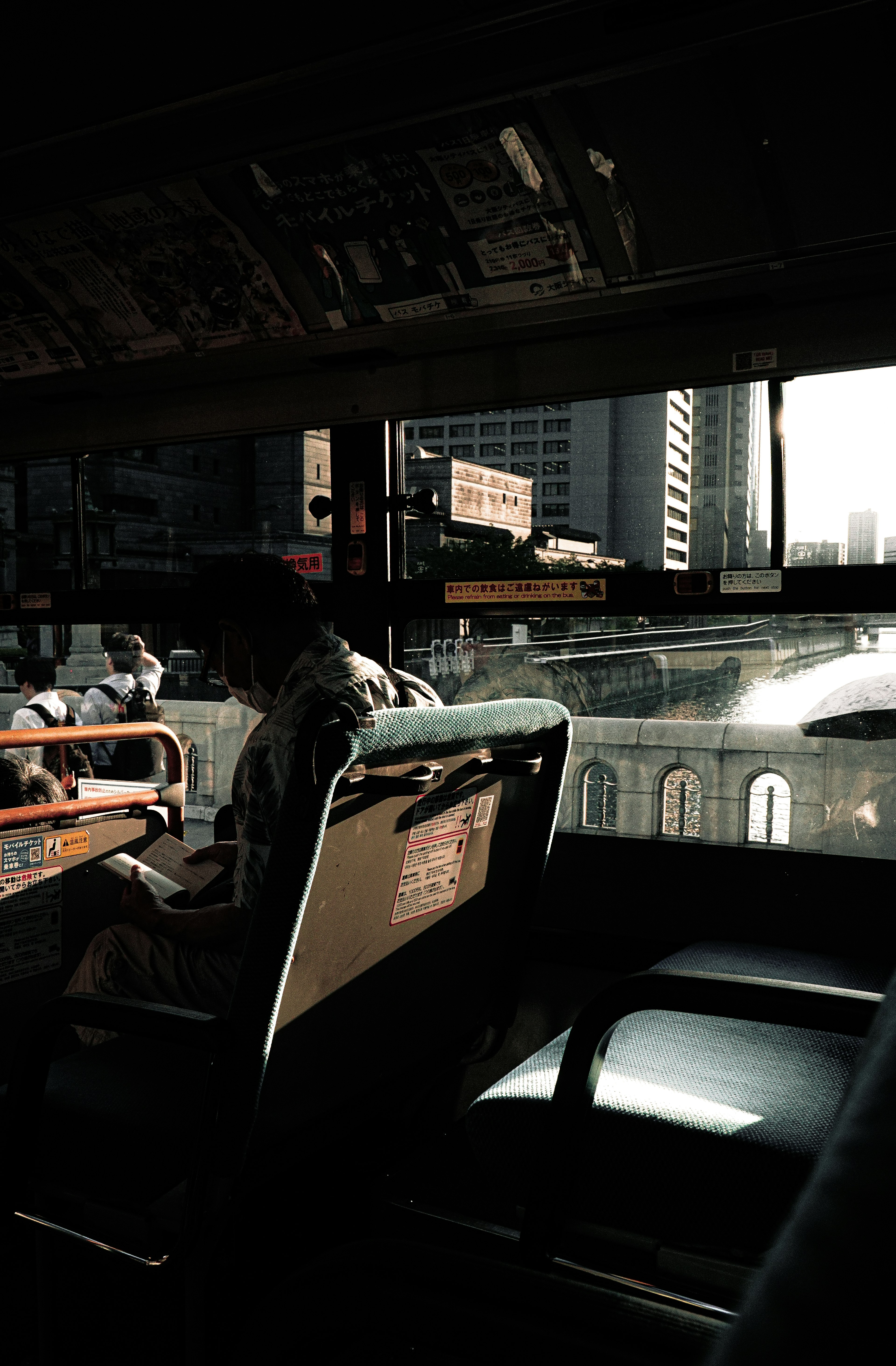 View from inside a bus showing passengers seated and cityscape outside