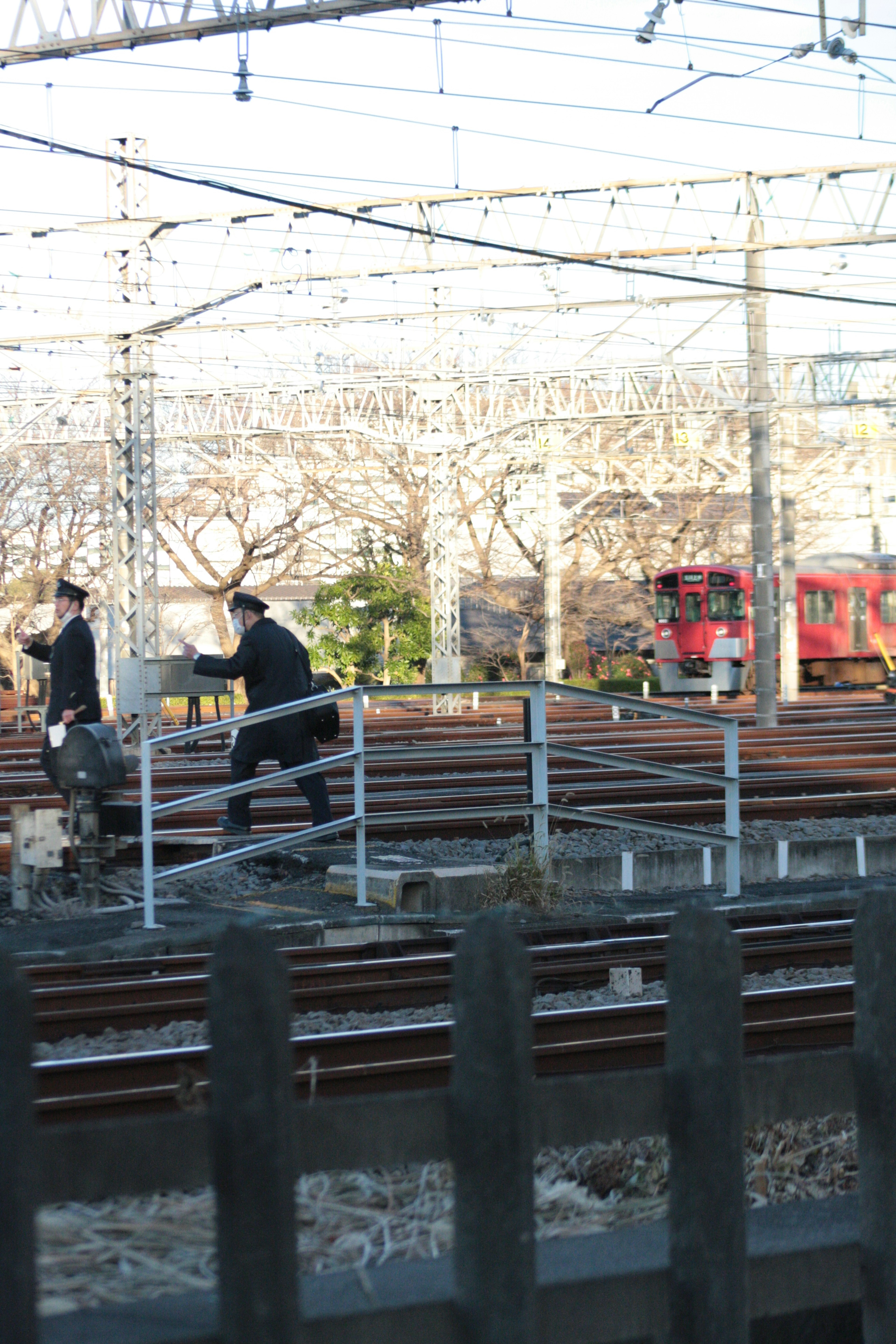 Two workers on railway tracks with surrounding overhead wires