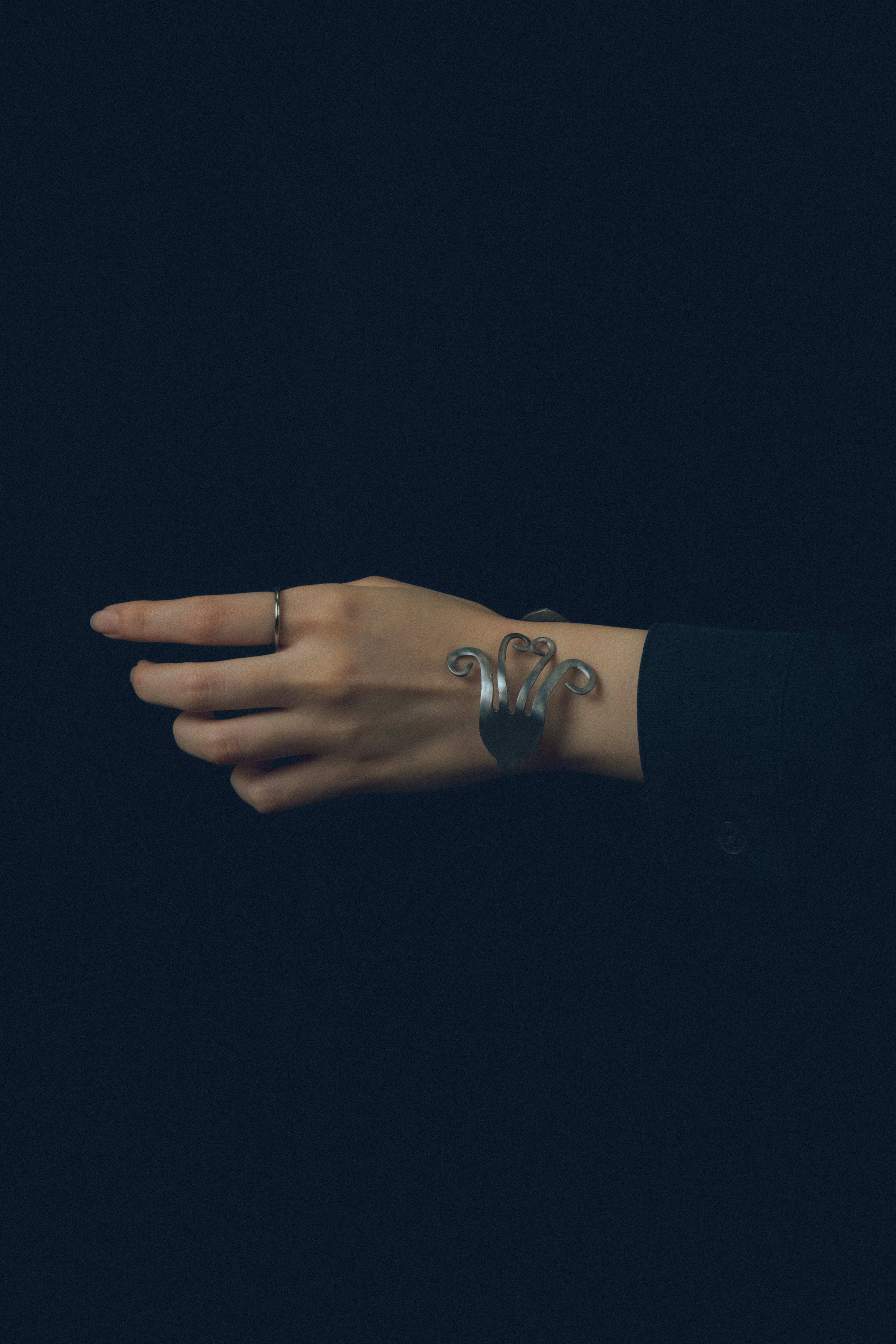 Image of a hand with a bracelet against a dark background