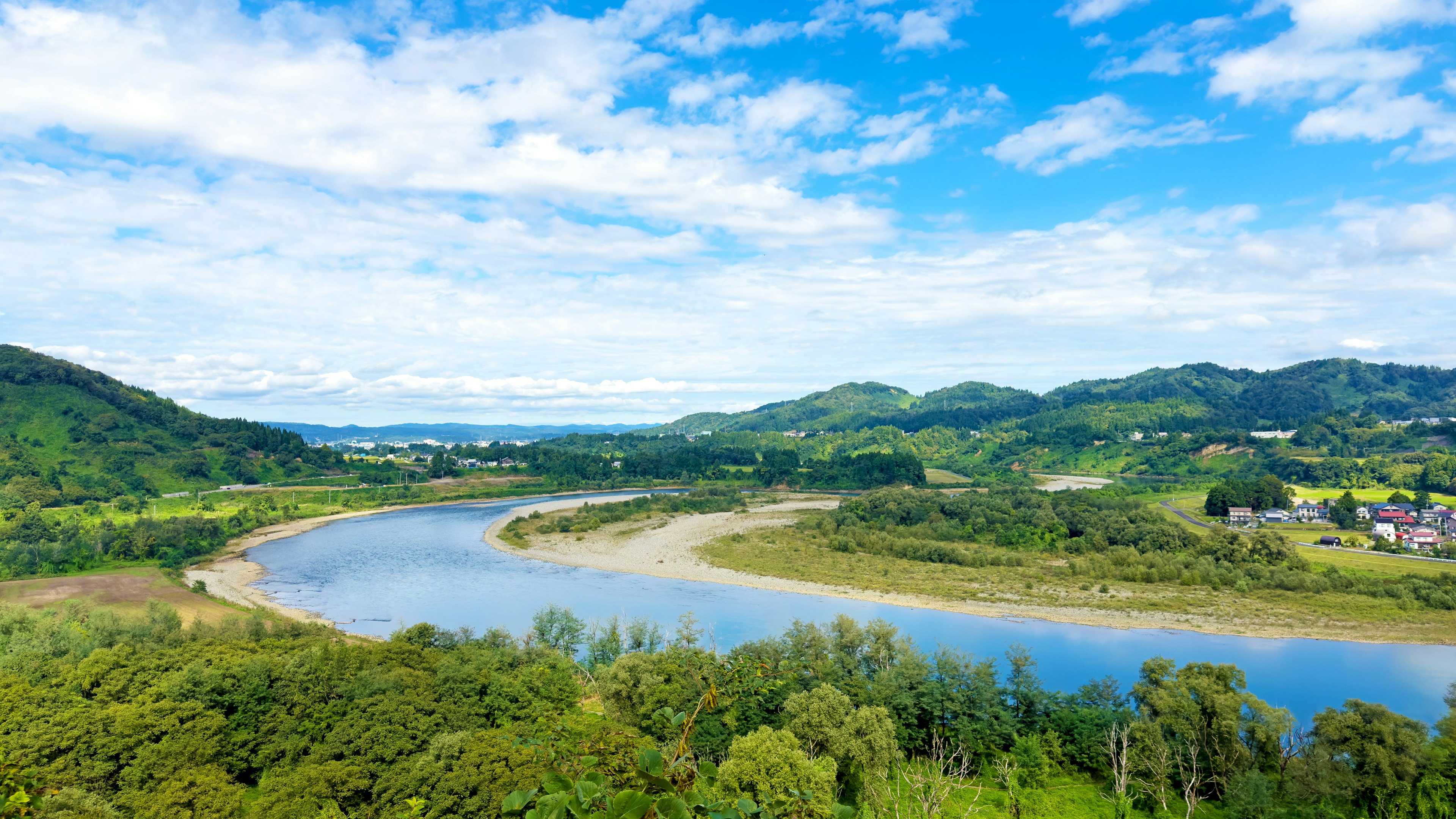 Vista panoramica di un fiume tortuoso circondato da vegetazione lussureggiante e cielo blu