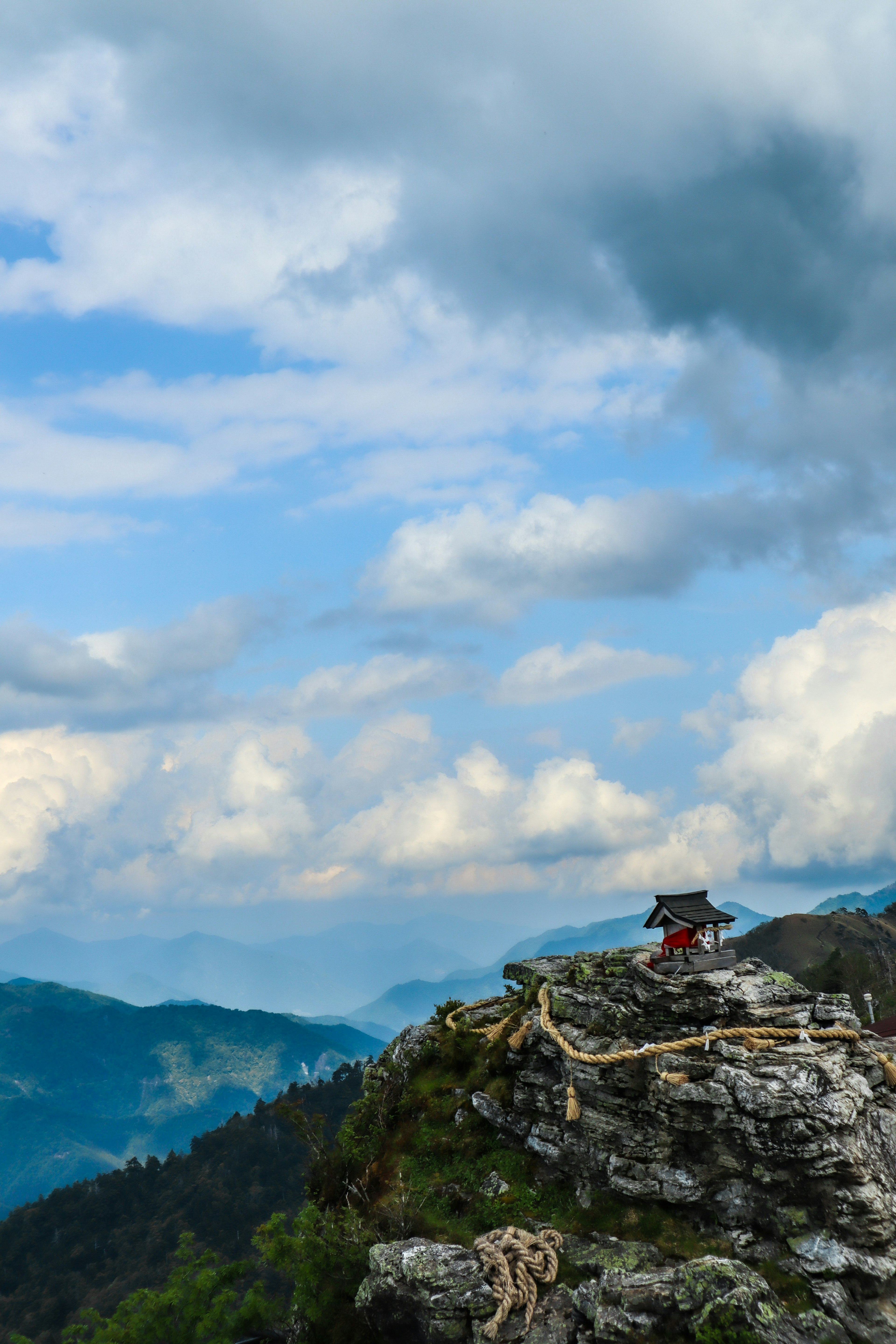 Scenic view of a small temple on a mountain peak with a blue sky and clouds