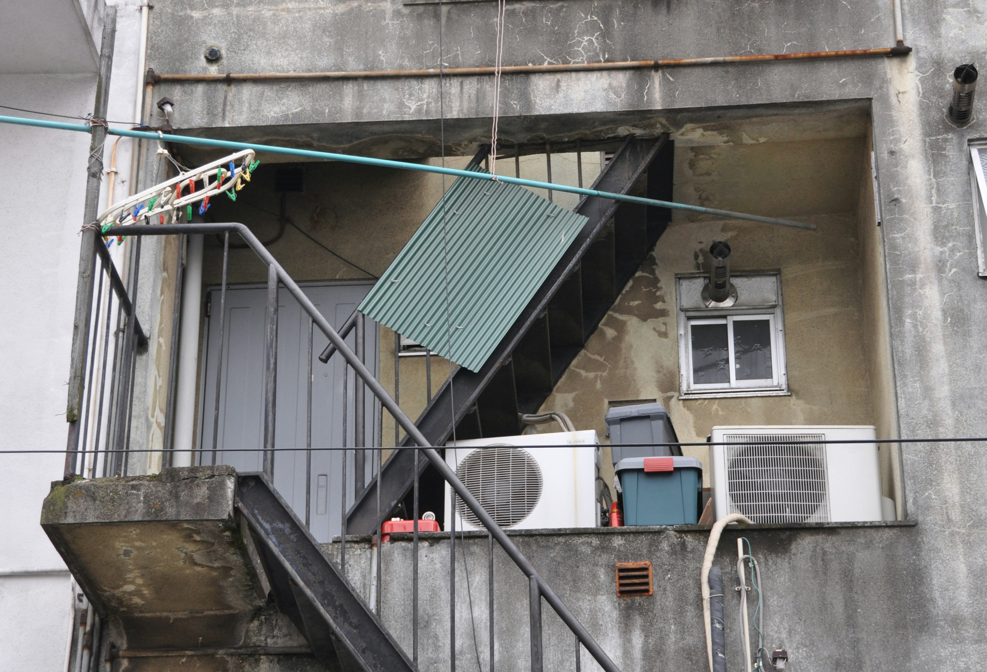 Vue extérieure d'un vieil appartement avec des escaliers et des climatiseurs