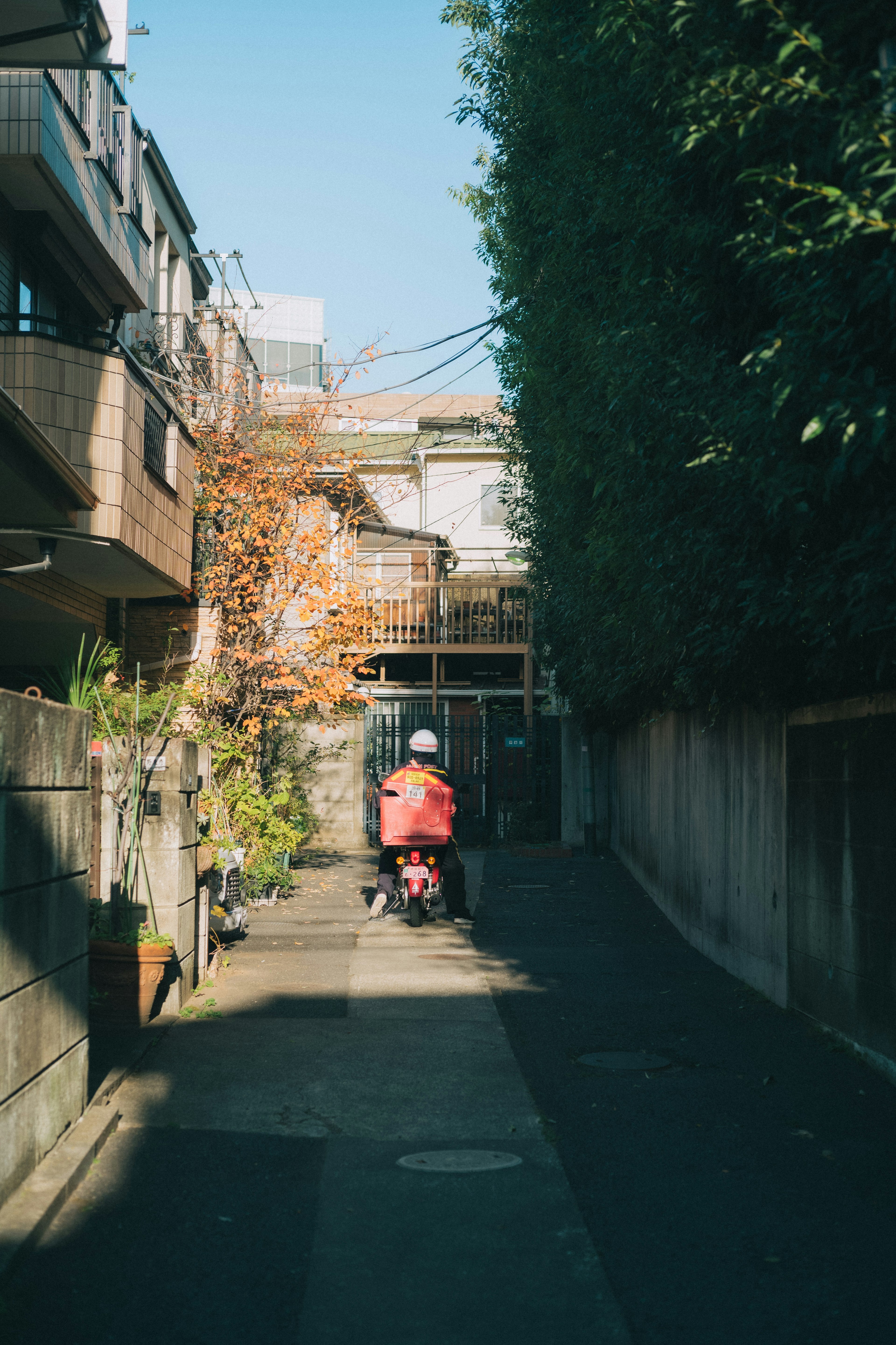 狭い路地を進む赤いスクーターと周囲の建物