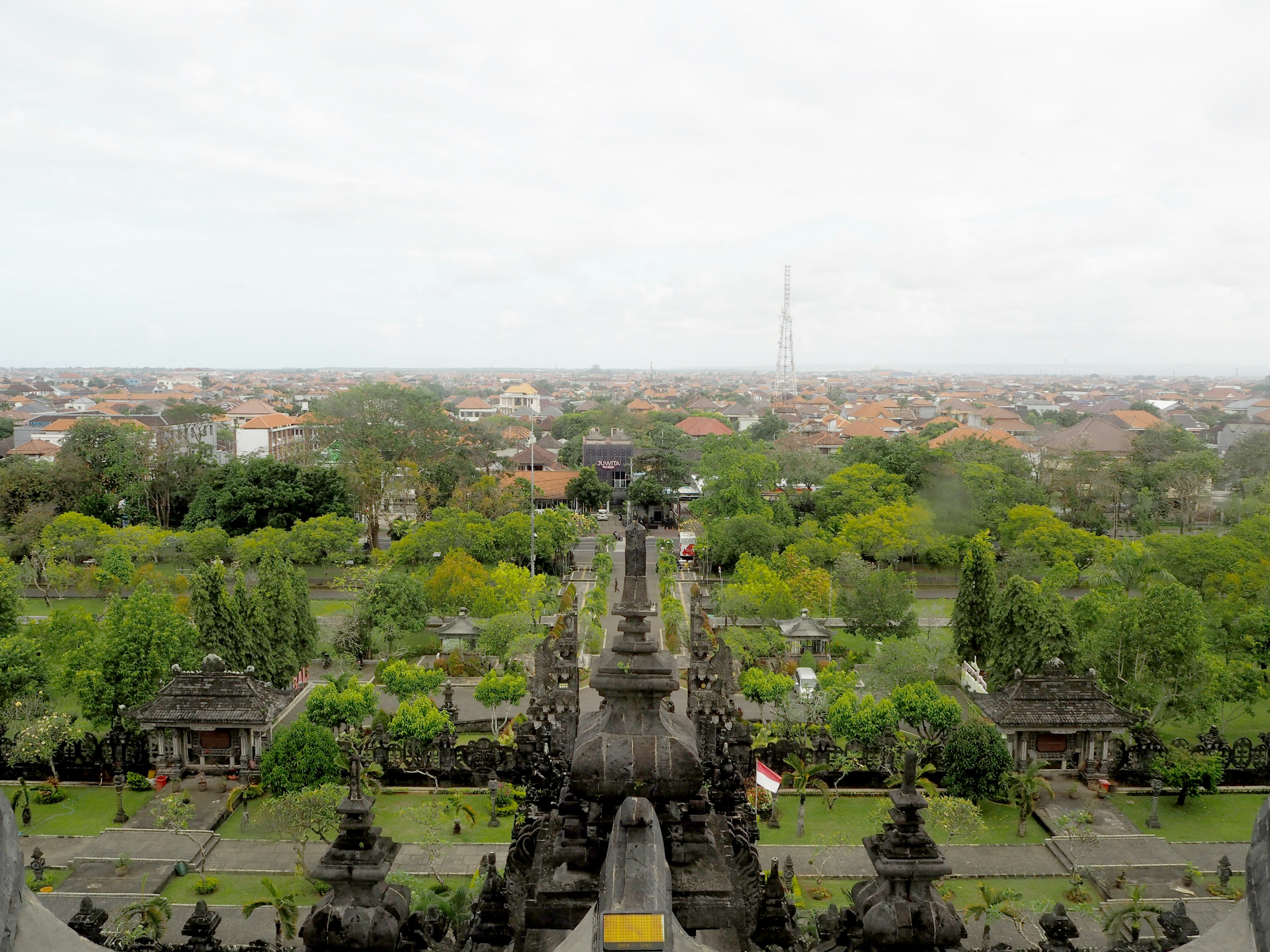 Scenic view of a Balinese temple with lush gardens and cityscape