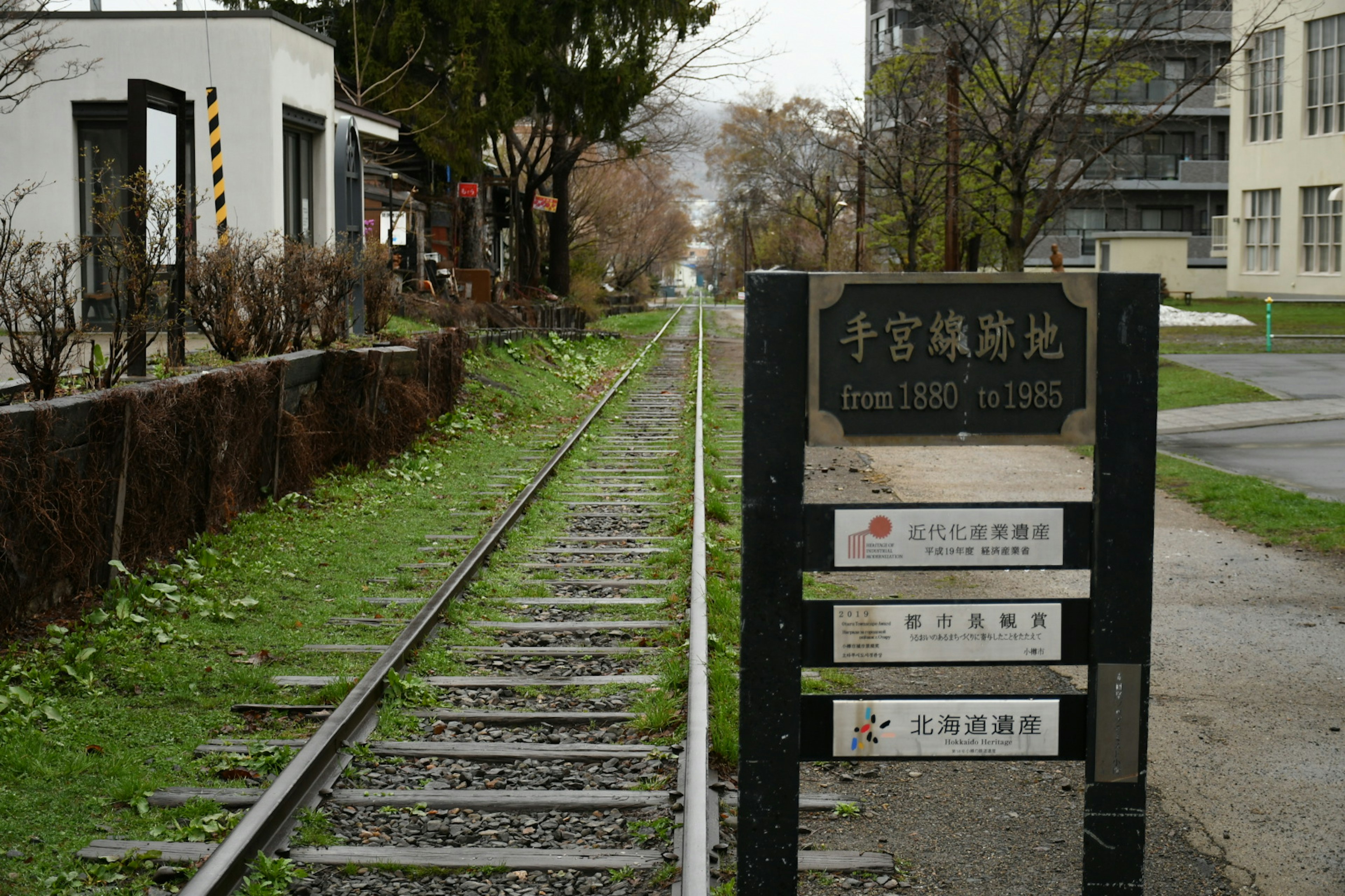 線路と案内板がある風景 緑の草と木々が周囲にある