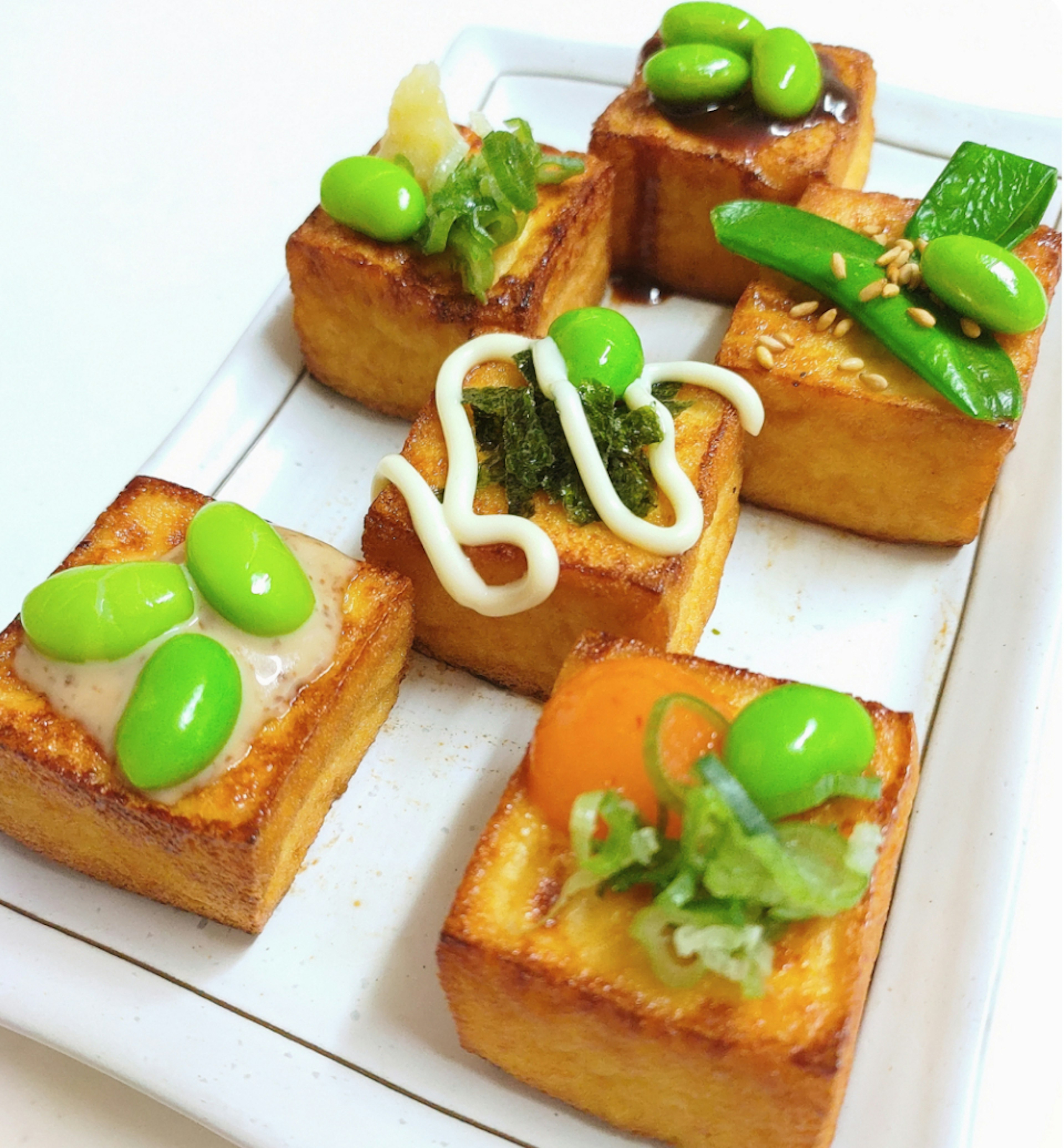 Surtido de cuadrados de tofu frito con coberturas verdes