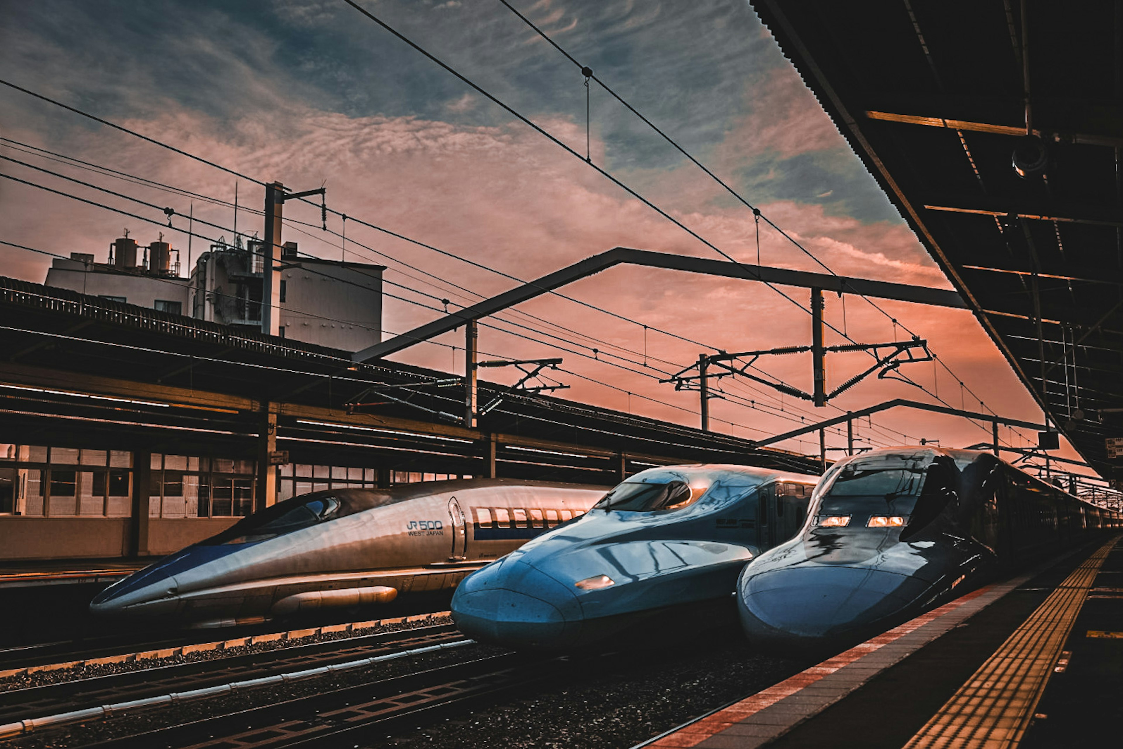 Shinkansen trains lined up under a sunset sky