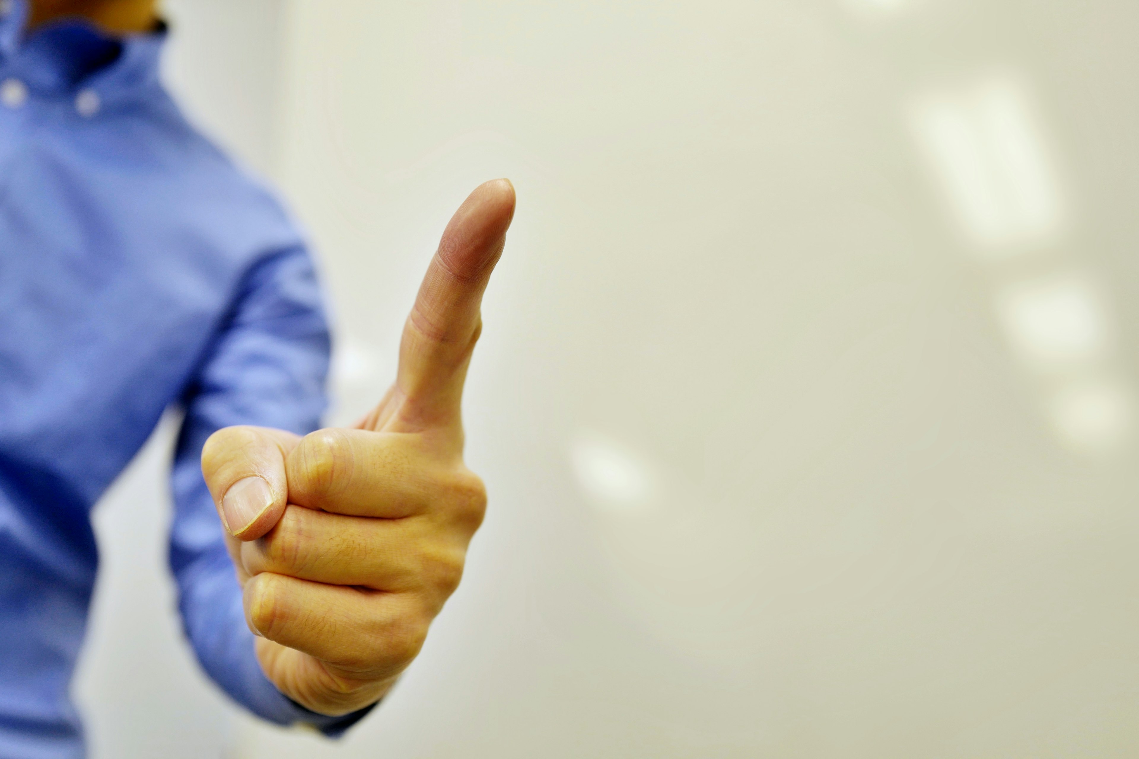 Close-up of a person in a blue shirt giving a thumbs up