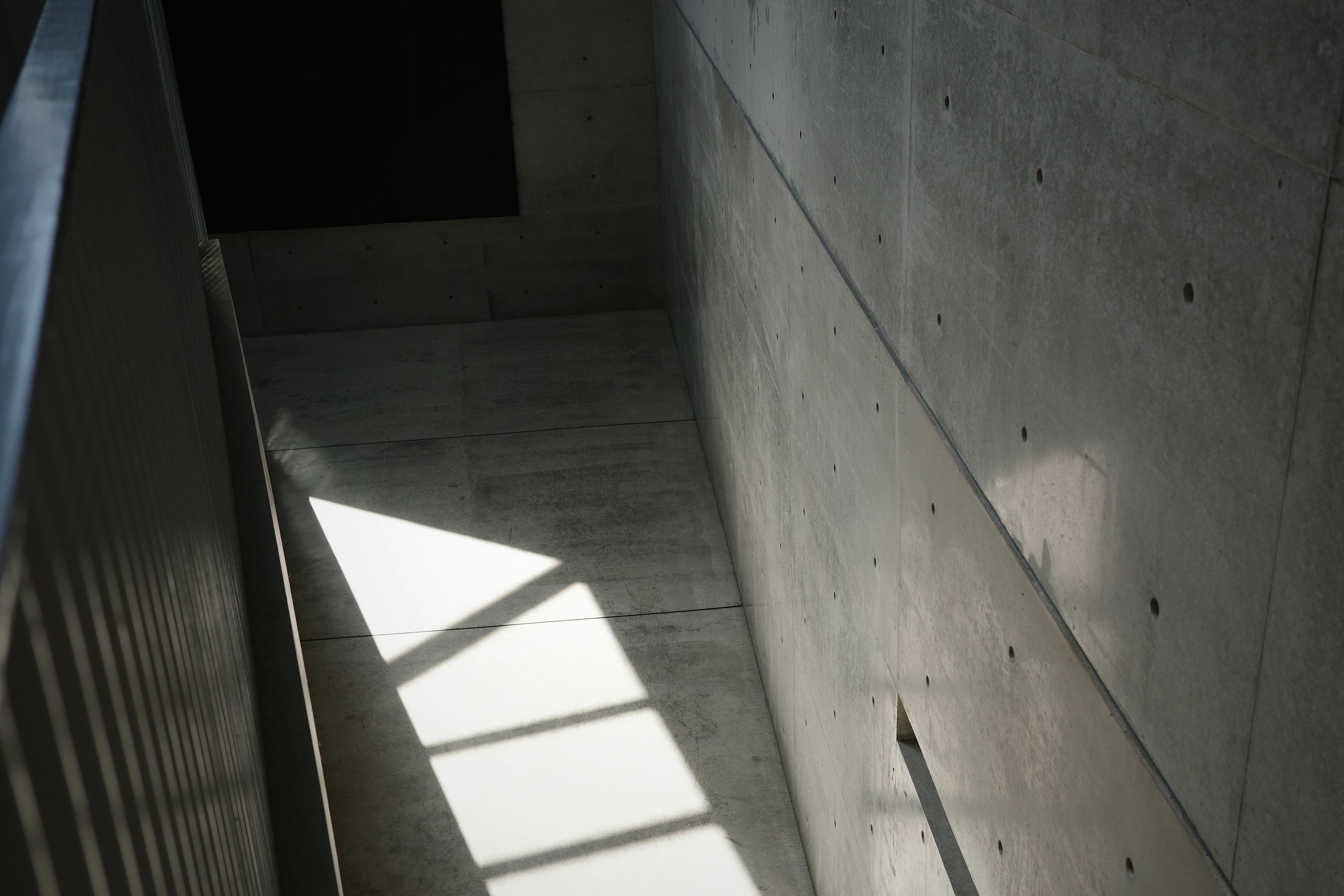 Escalera con paredes y suelo de concreto iluminados por luz en ángulo