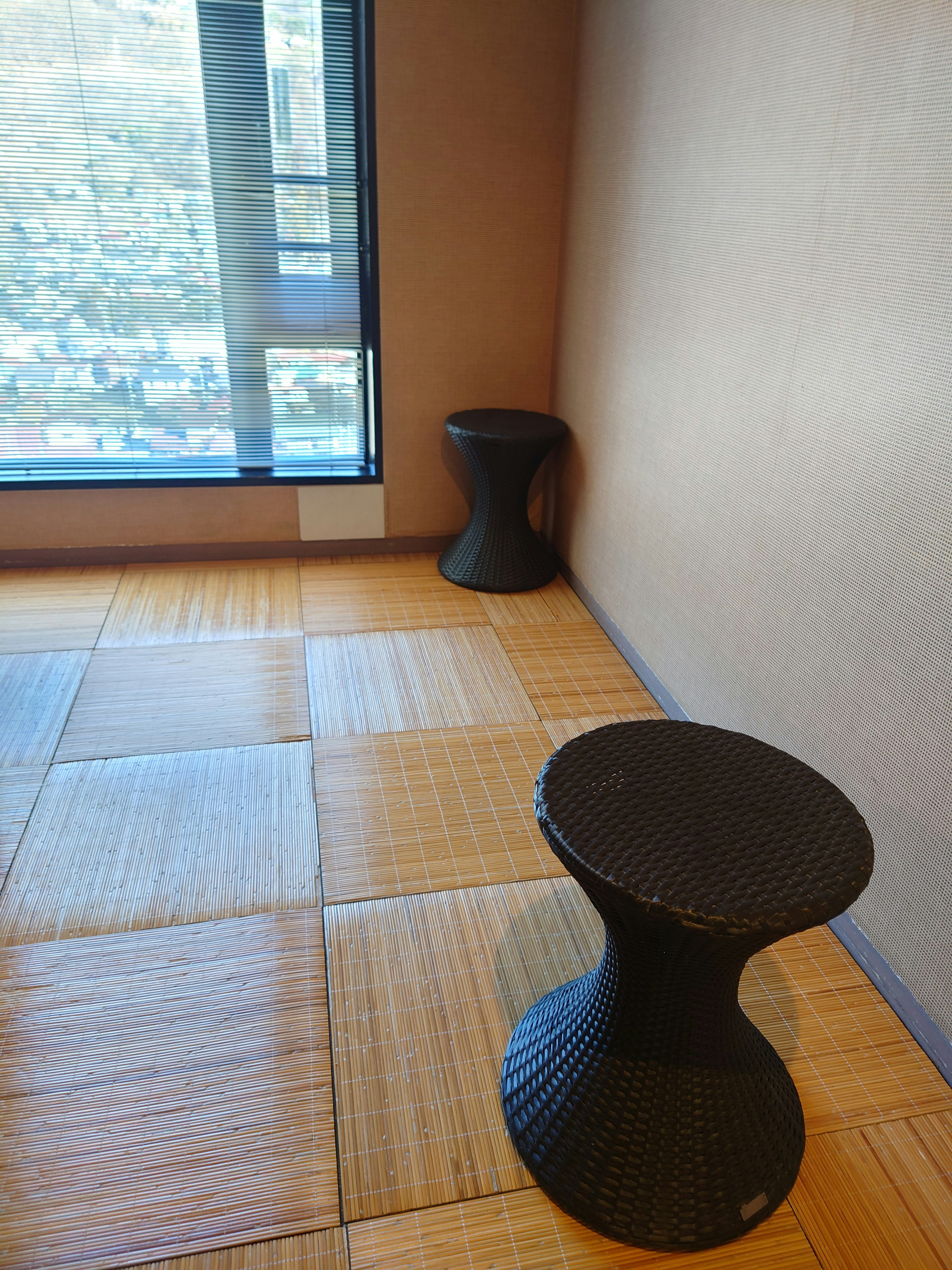 Two black stools in the corner of a room with tatami flooring