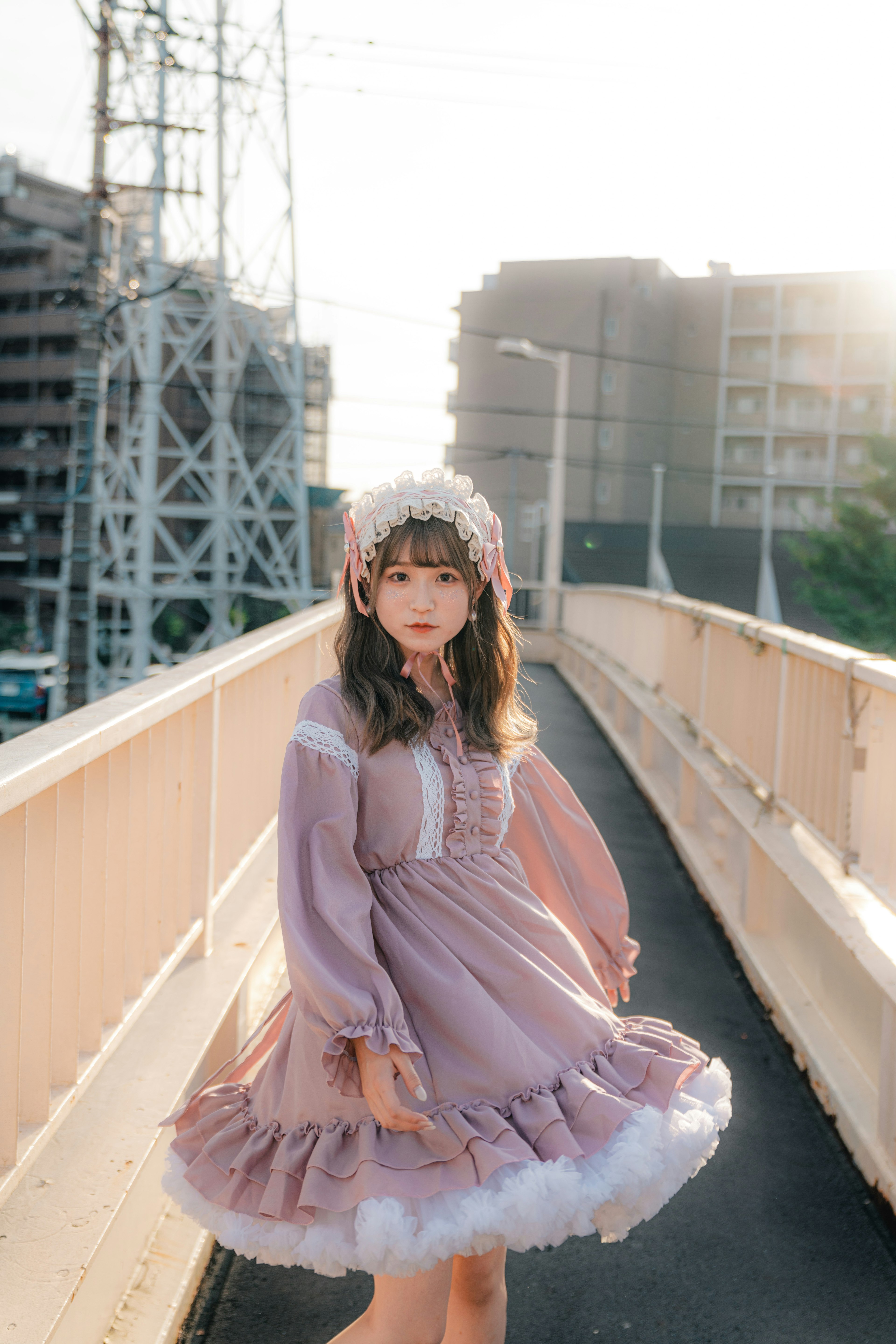 A woman in a Lolita dress stands on a bridge