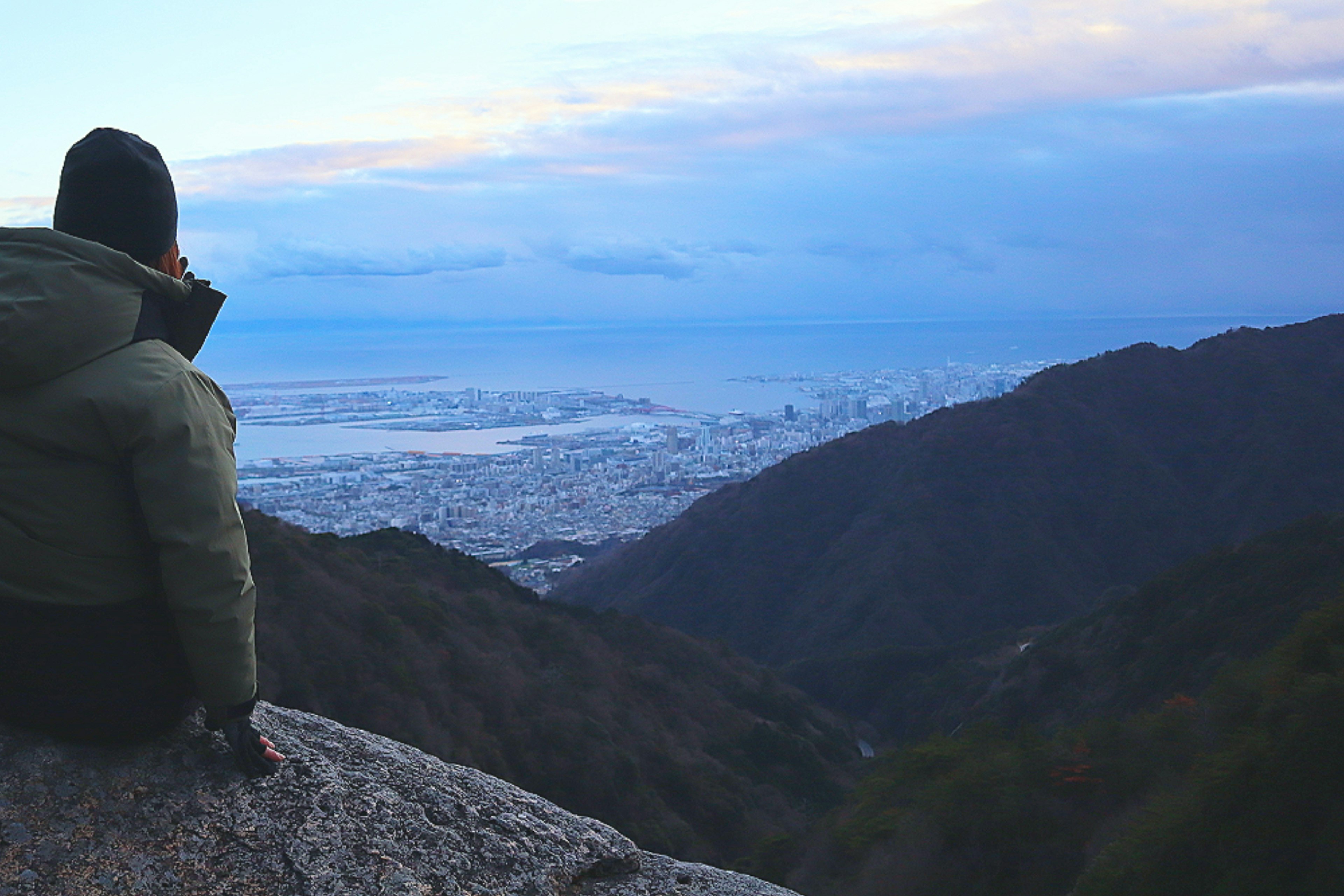 Una persona sentada en una roca con vista panorámica desde una montaña