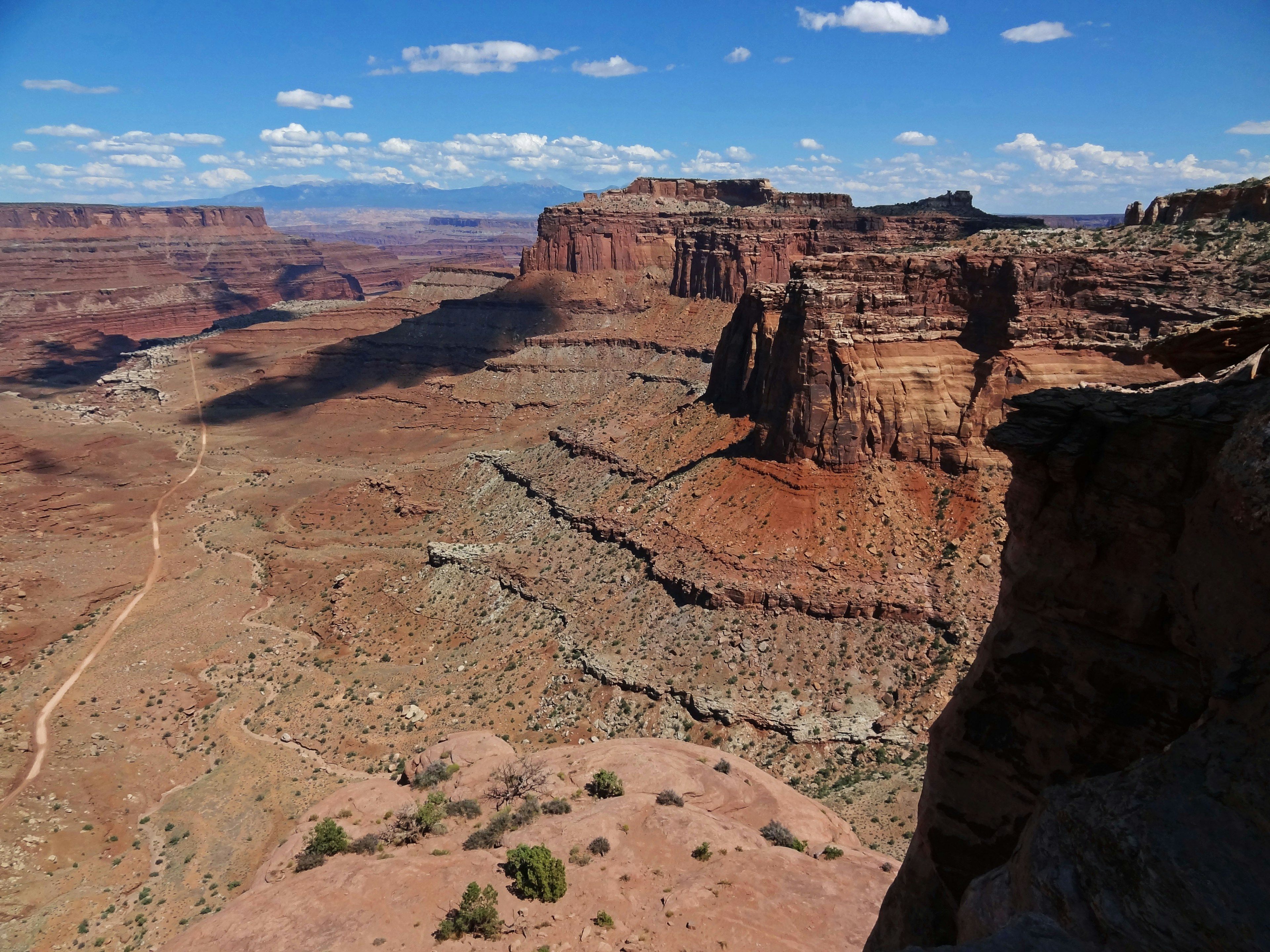 Vue expansive d'un canyon de roches rouges avec des falaises en couches et un ciel bleu