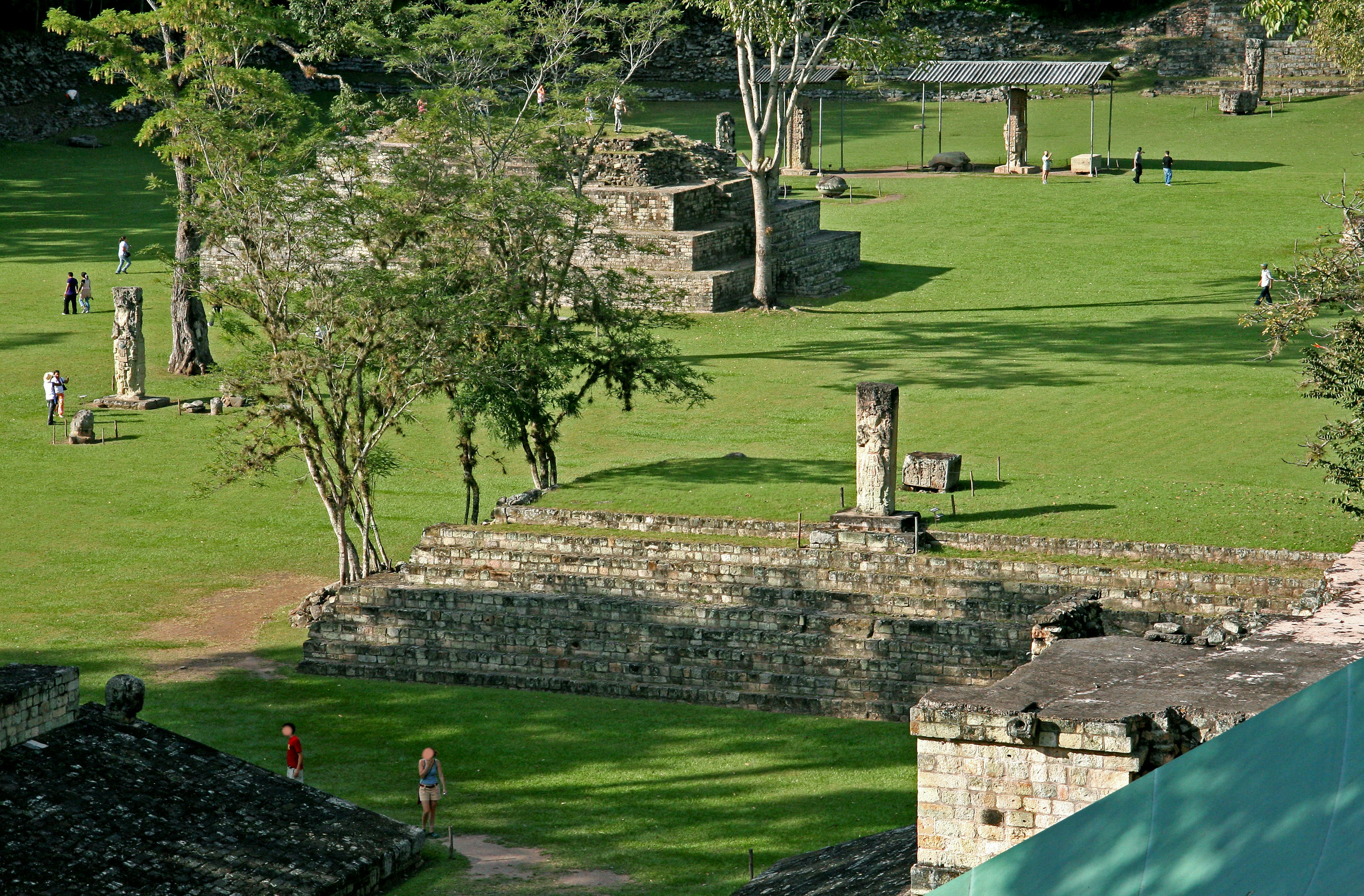 Ruinas antiguas en un prado verde con personas caminando