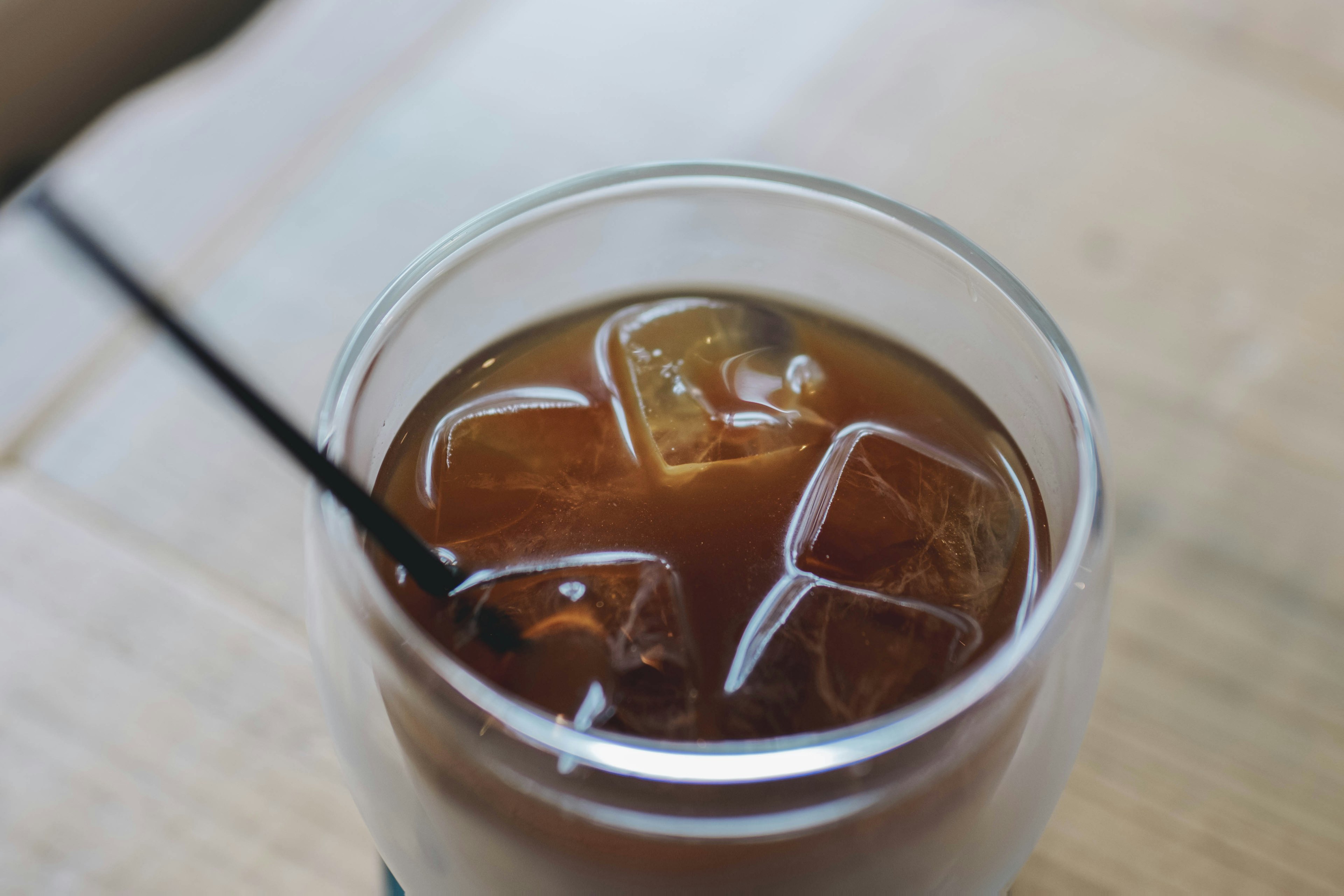 Glass of iced tea with ice cubes and a black straw