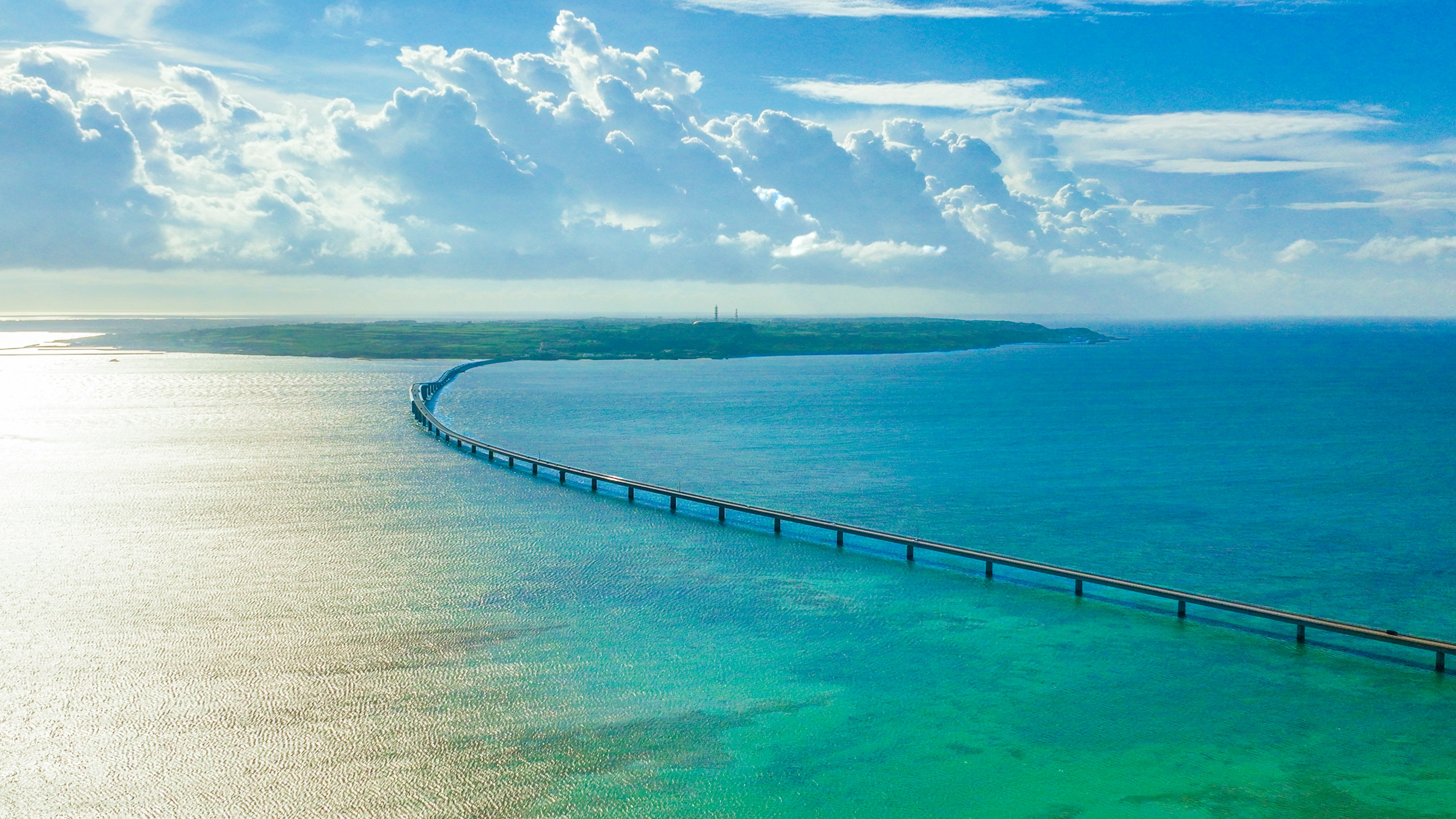 Jembatan panjang membentang di atas lautan biru di bawah langit cerah