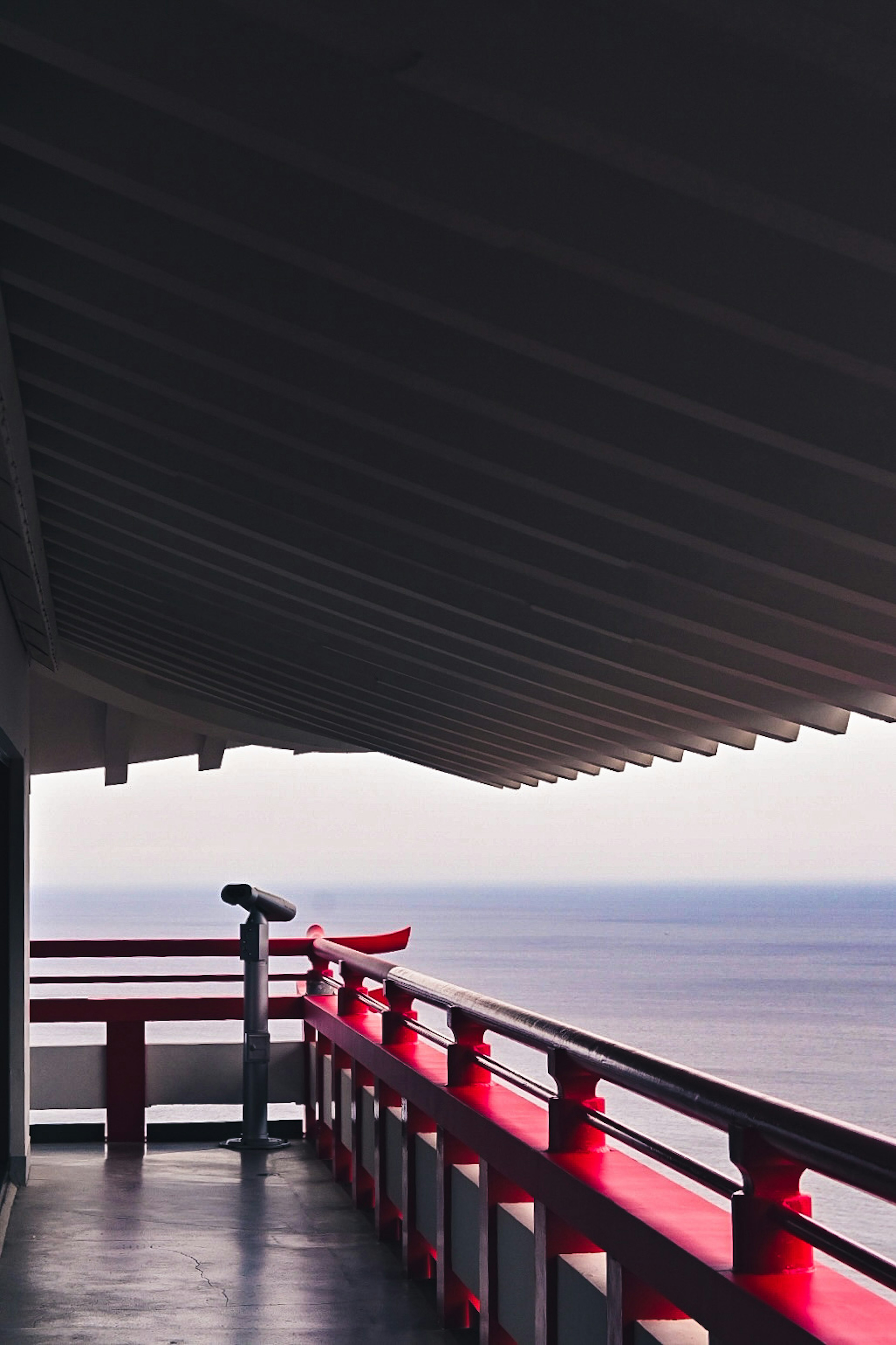 View from a balcony with red railing overlooking the ocean