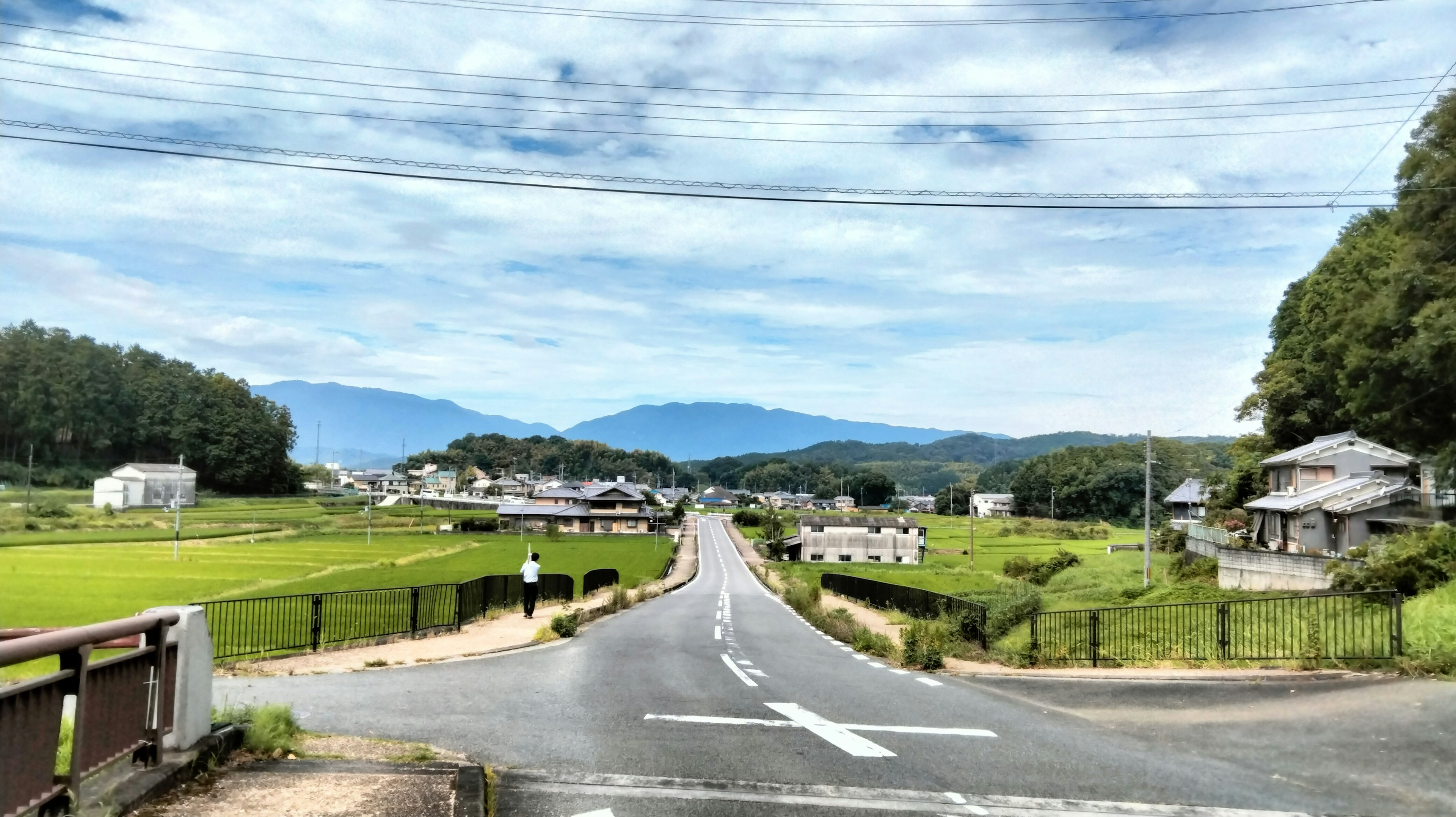 一条穿过绿色田野的乡村道路，背景是山脉