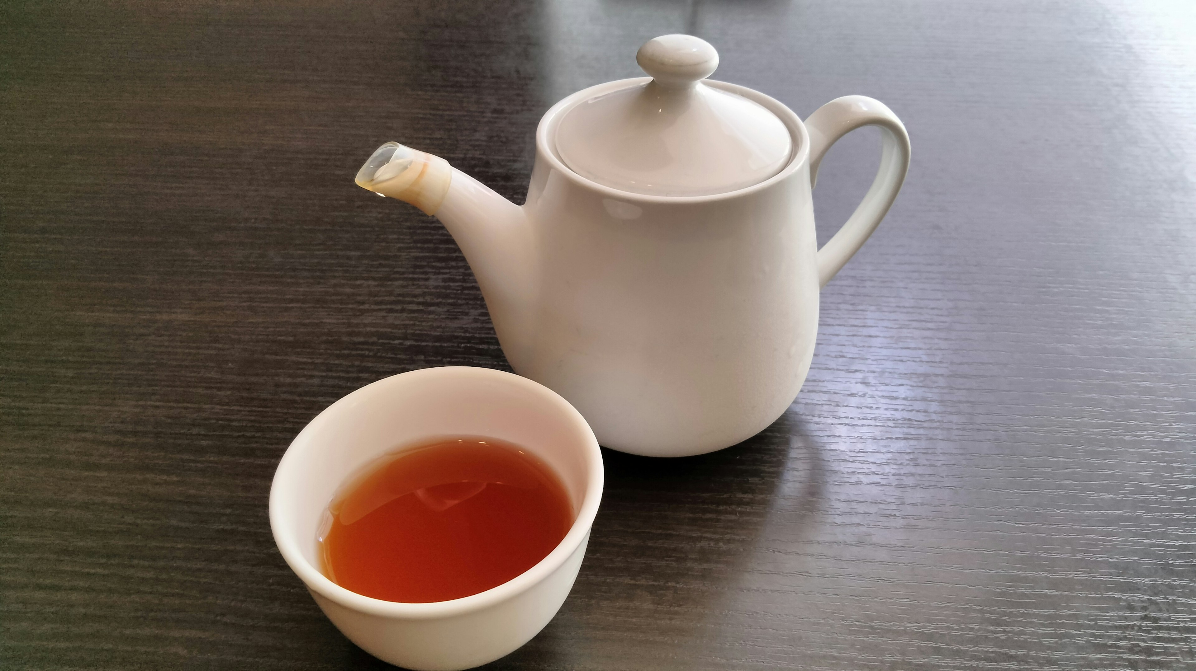 Teapot putih dan mangkuk teh diletakkan di atas meja