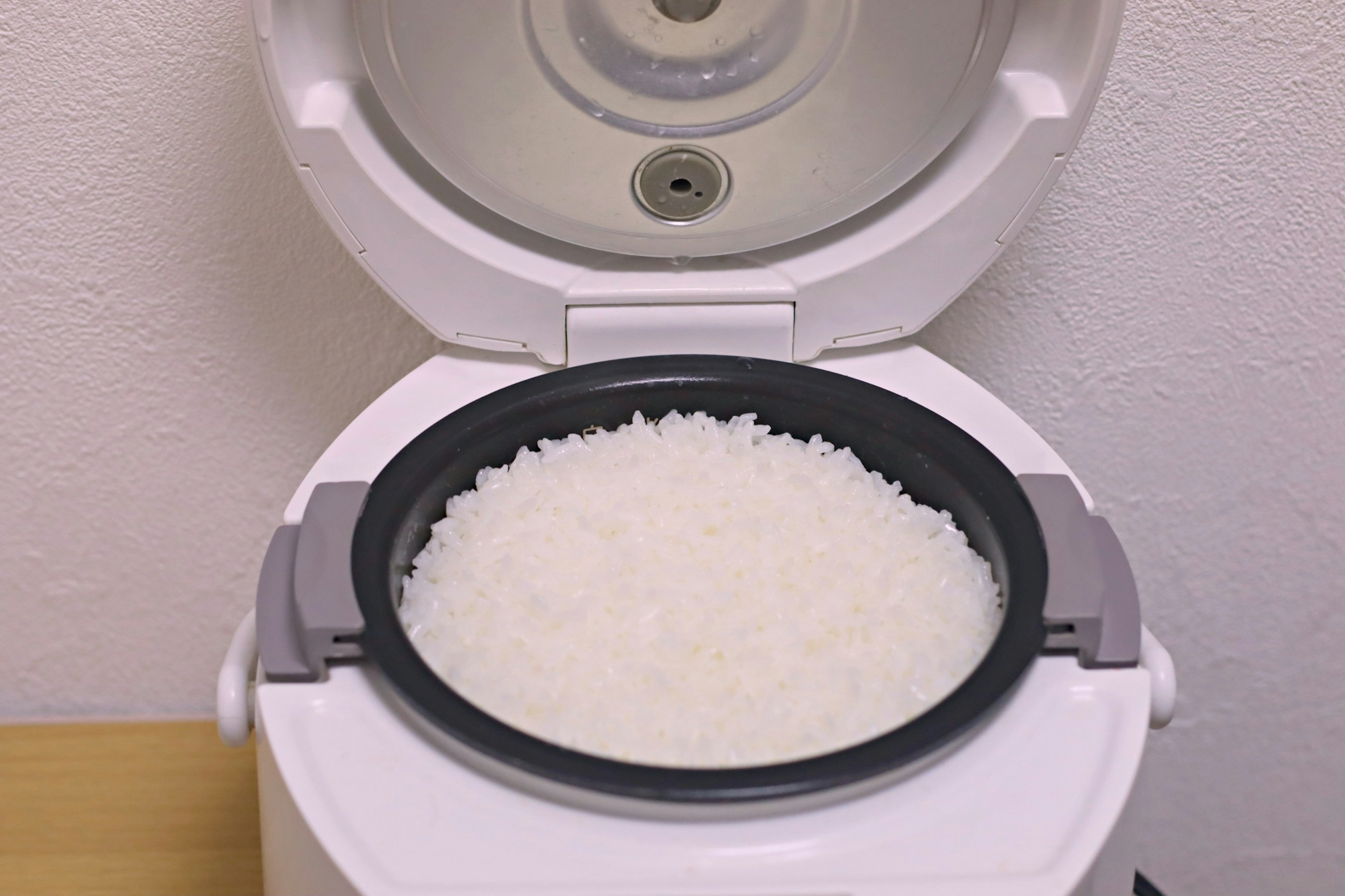 Inside a rice cooker with cooked white rice